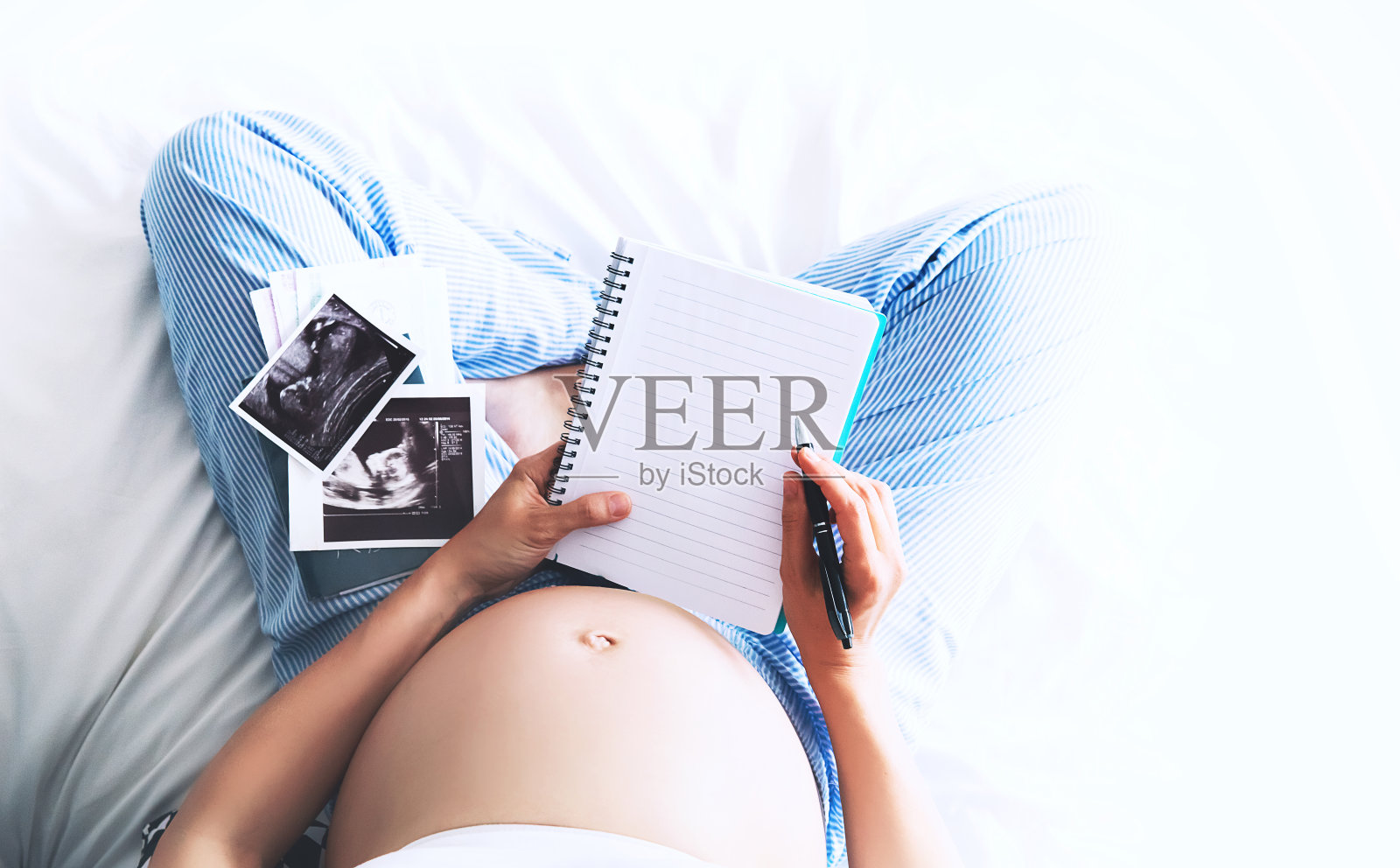 孕妇在笔记本上做笔记，拿着超声图像和医疗文件照片摄影图片