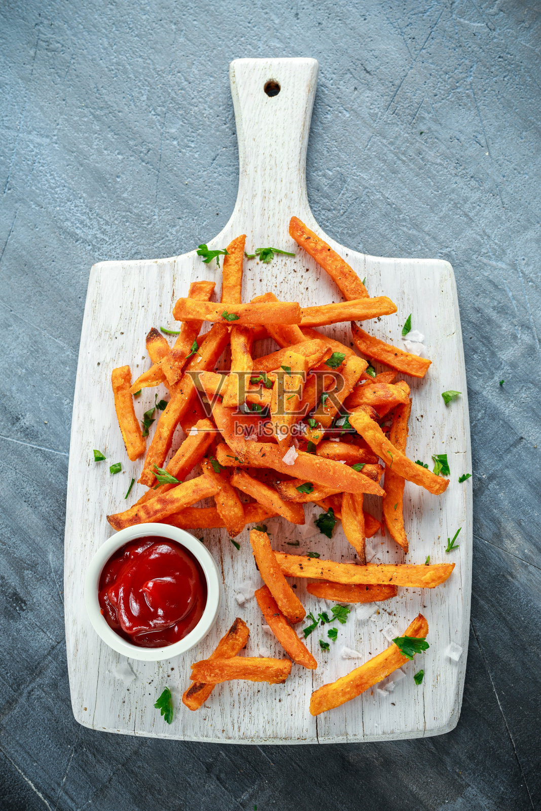 健康自制烤橙甘薯薯条配番茄酱，盐，胡椒在白色木板上照片摄影图片