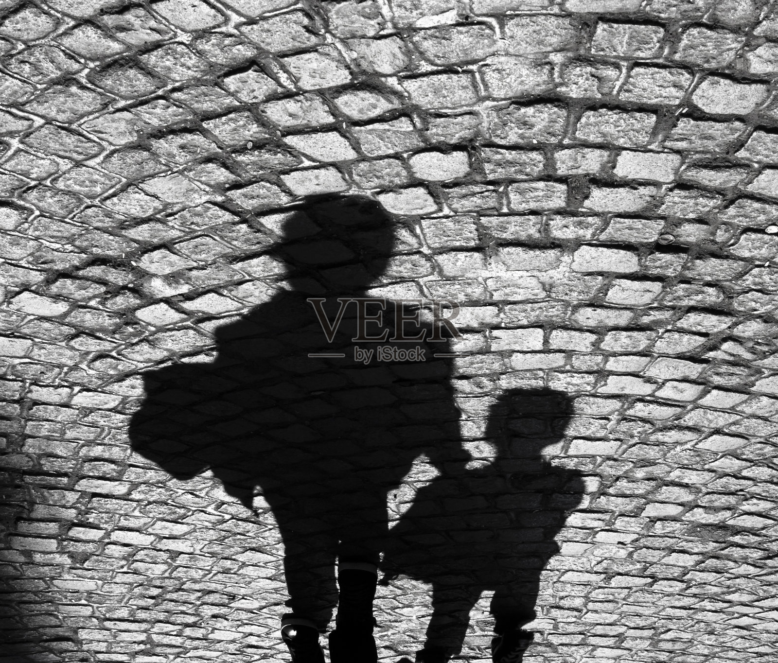 一个大人和一个小孩在鹅卵石人行道上的影子照片摄影图片