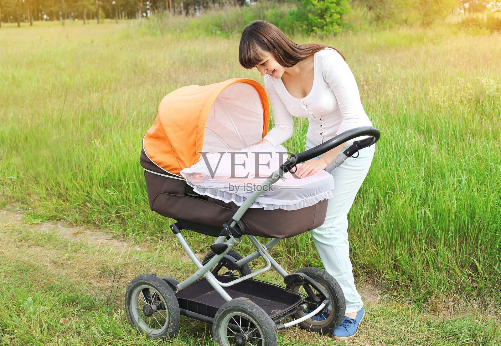 快乐的年轻微笑母亲与婴儿婴儿车走在户外照片摄影图片
