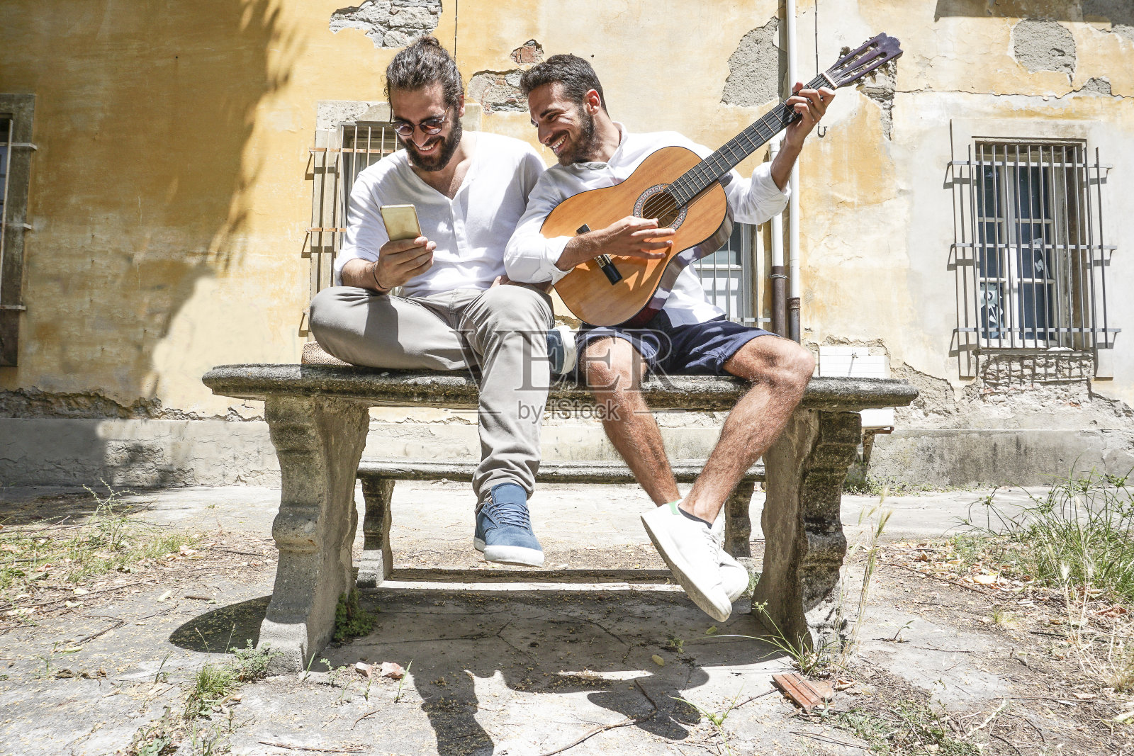 两个成年男子一边弹吉他一边打电话照片摄影图片