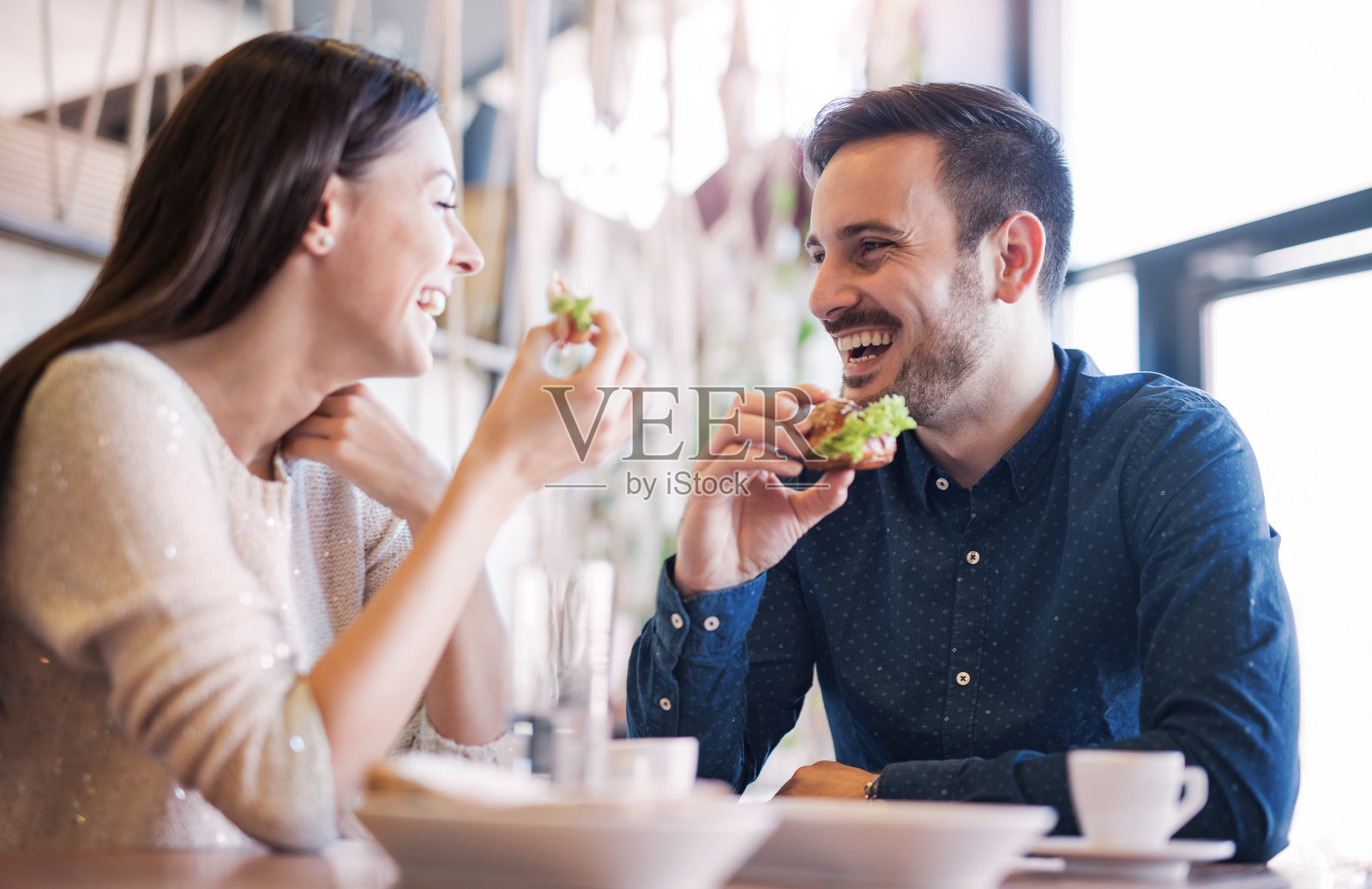 一对年轻漂亮的夫妇坐在咖啡馆里吃早餐。爱,食物,生活方式照片摄影图片