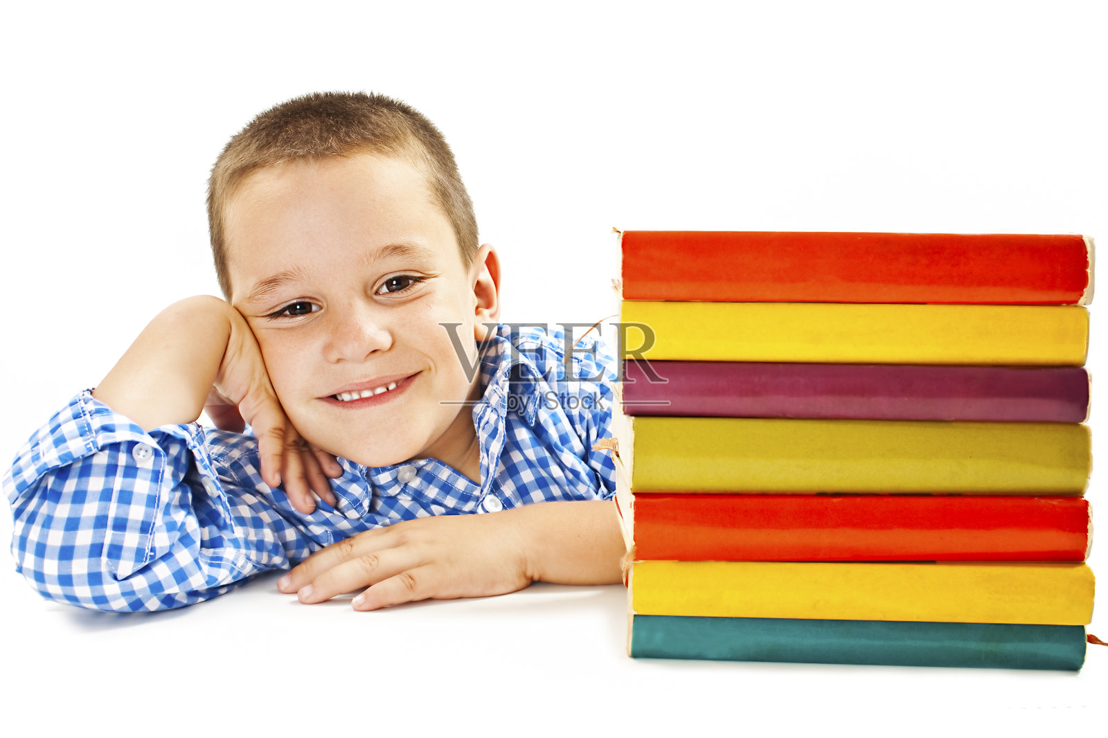 小男孩面带微笑，桌上放着课本照片摄影图片
