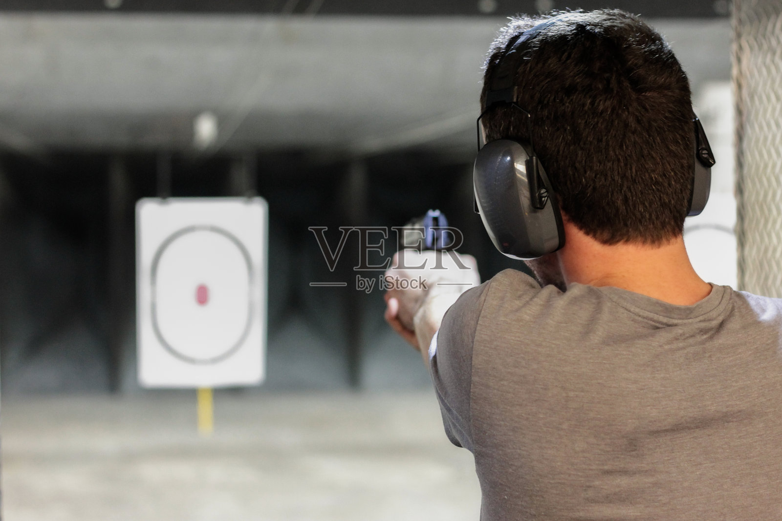 在室内射击场，一名男子用usp手枪向目标射击照片摄影图片