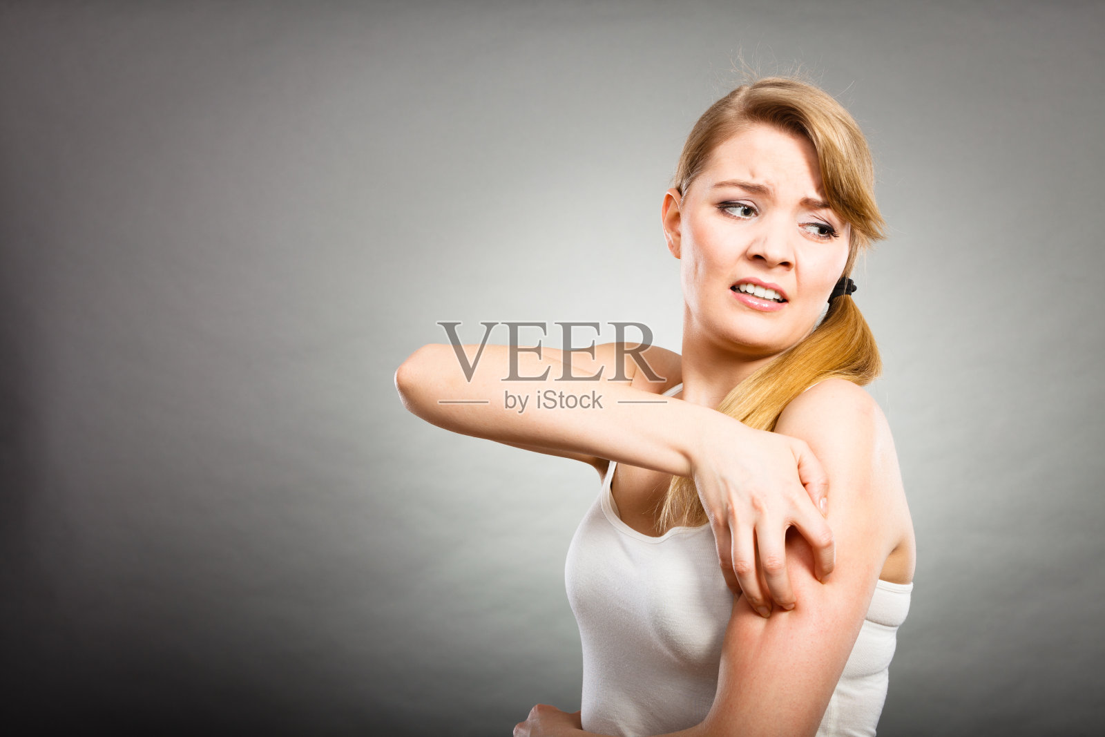一个女人用过敏皮疹挠她发痒的手臂照片摄影图片