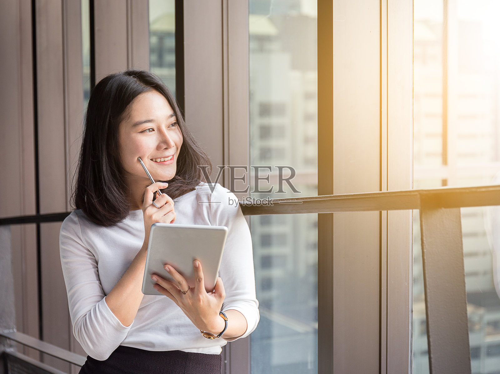 微笑商务女性正在现代办公室用平板电脑思考照片摄影图片
