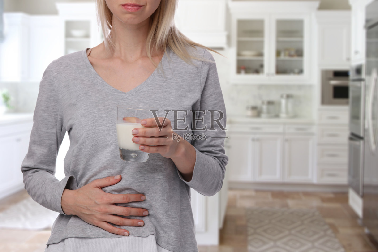 乳制品不宽容的人。胃痛的女人拿着一杯牛奶。乳糖不耐症，保健理念。照片摄影图片