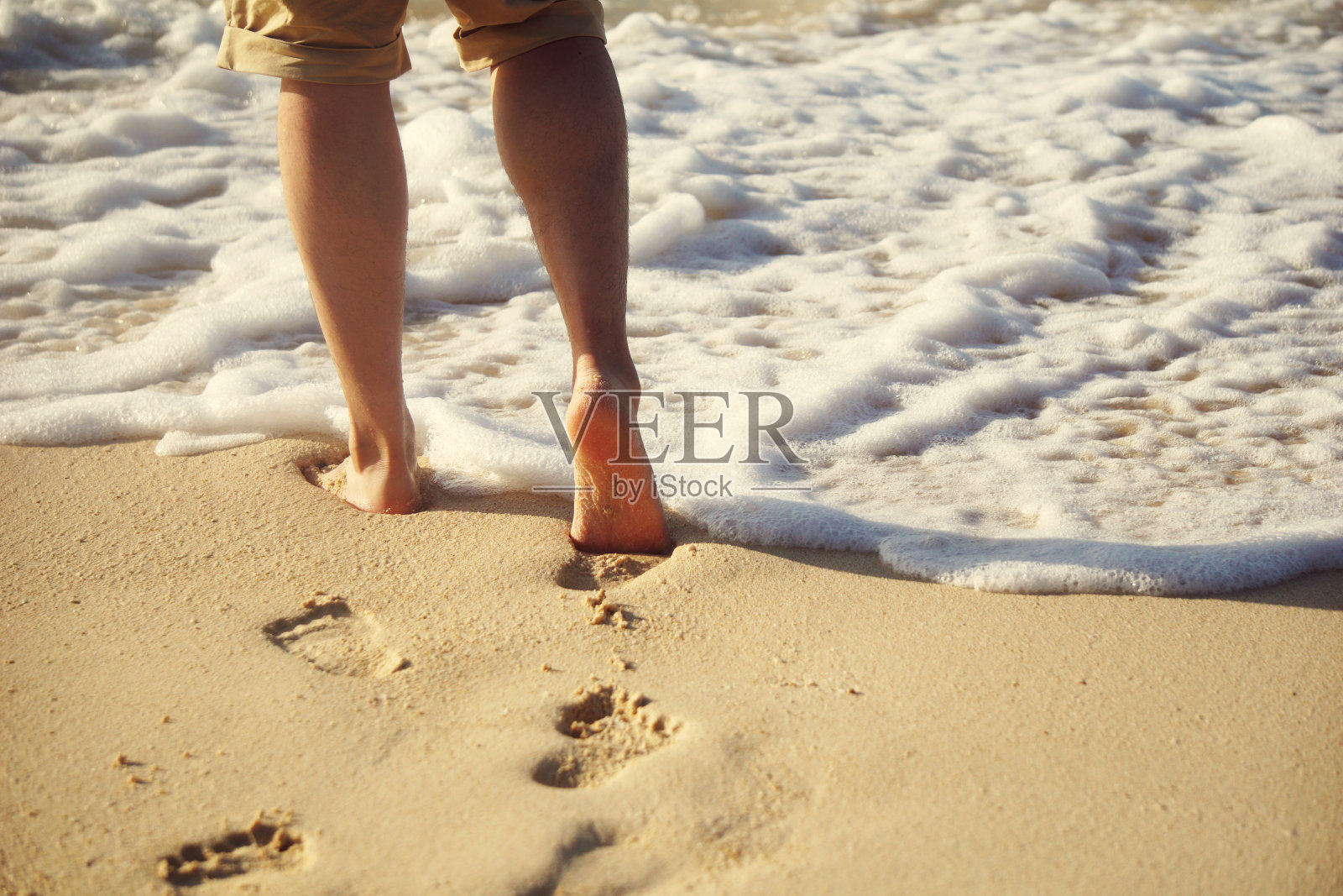 人走在潮湿的沙滩上，留下脚印照片摄影图片