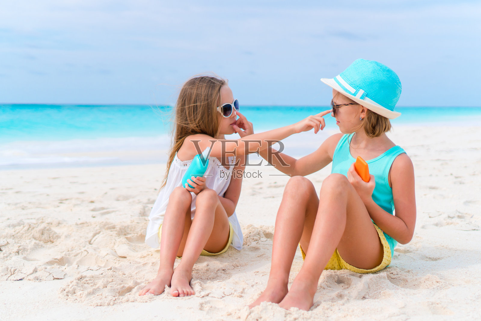 孩子们在海滩上互相涂防晒霜。防止紫外线辐射的概念照片摄影图片