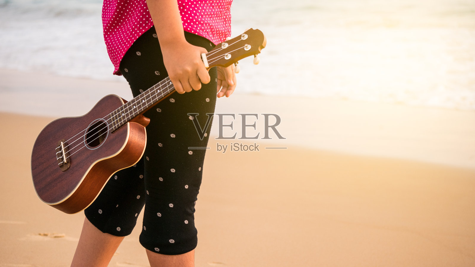 女人或女孩在海滩上玩尤克里里在假期和放松的概念日落时间。照片摄影图片