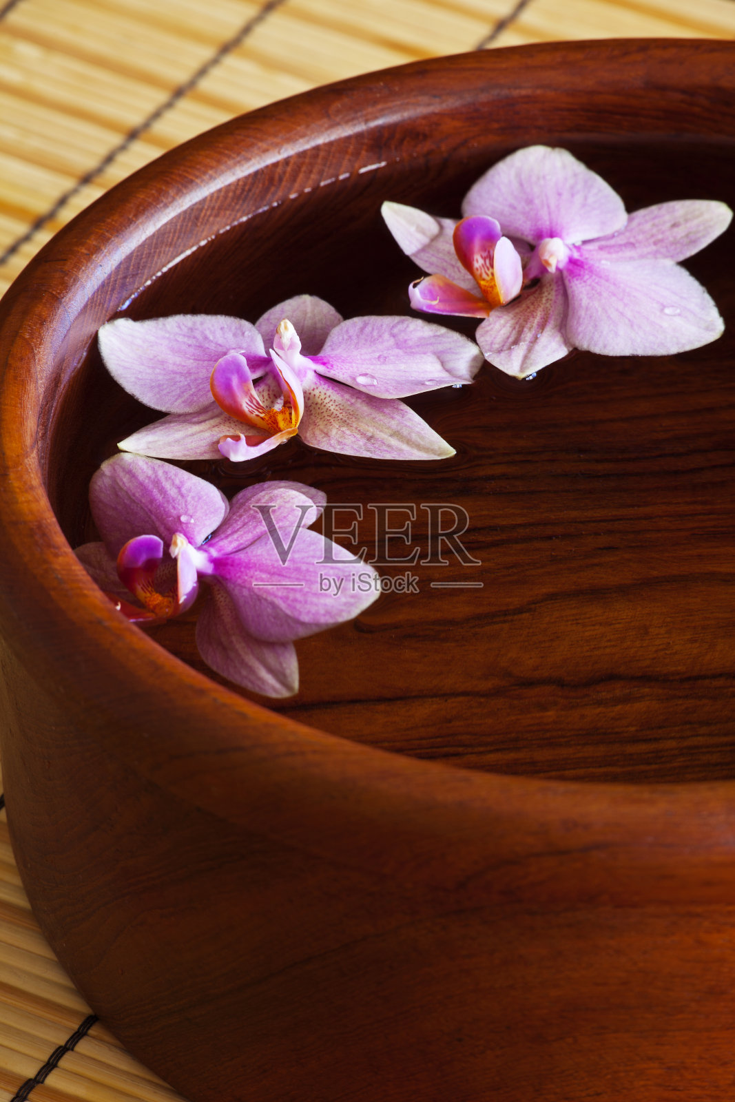 紫色的兰花漂浮在木碗里照片摄影图片