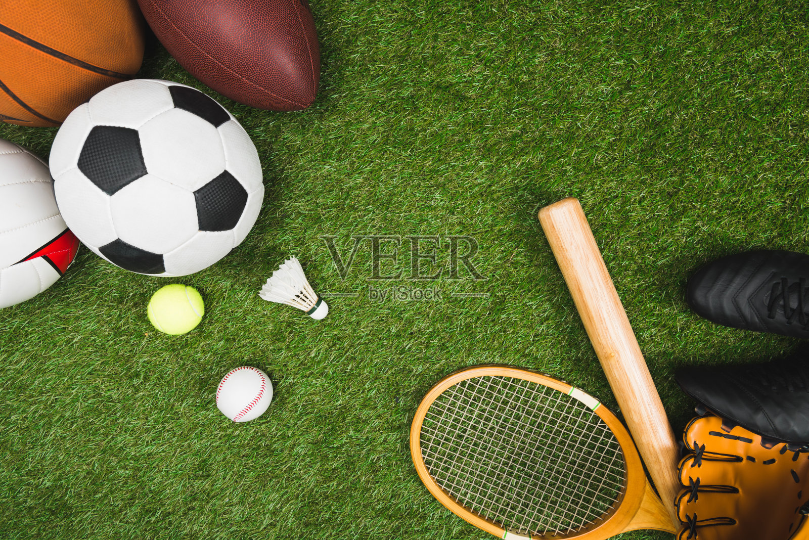 俯视图各种运动球，棒球拍和手套，羽毛球拍在绿色草坪上照片摄影图片