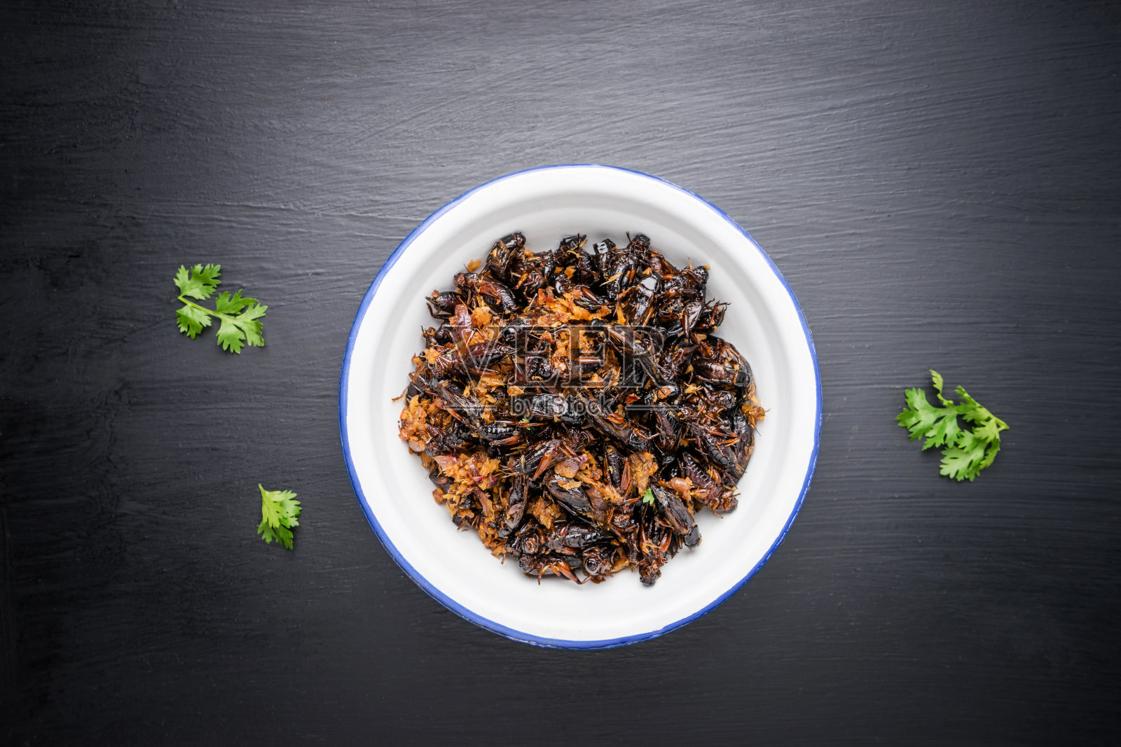 食虫，木桌上铁碗里炸蟋蟀，泰国菜。照片摄影图片