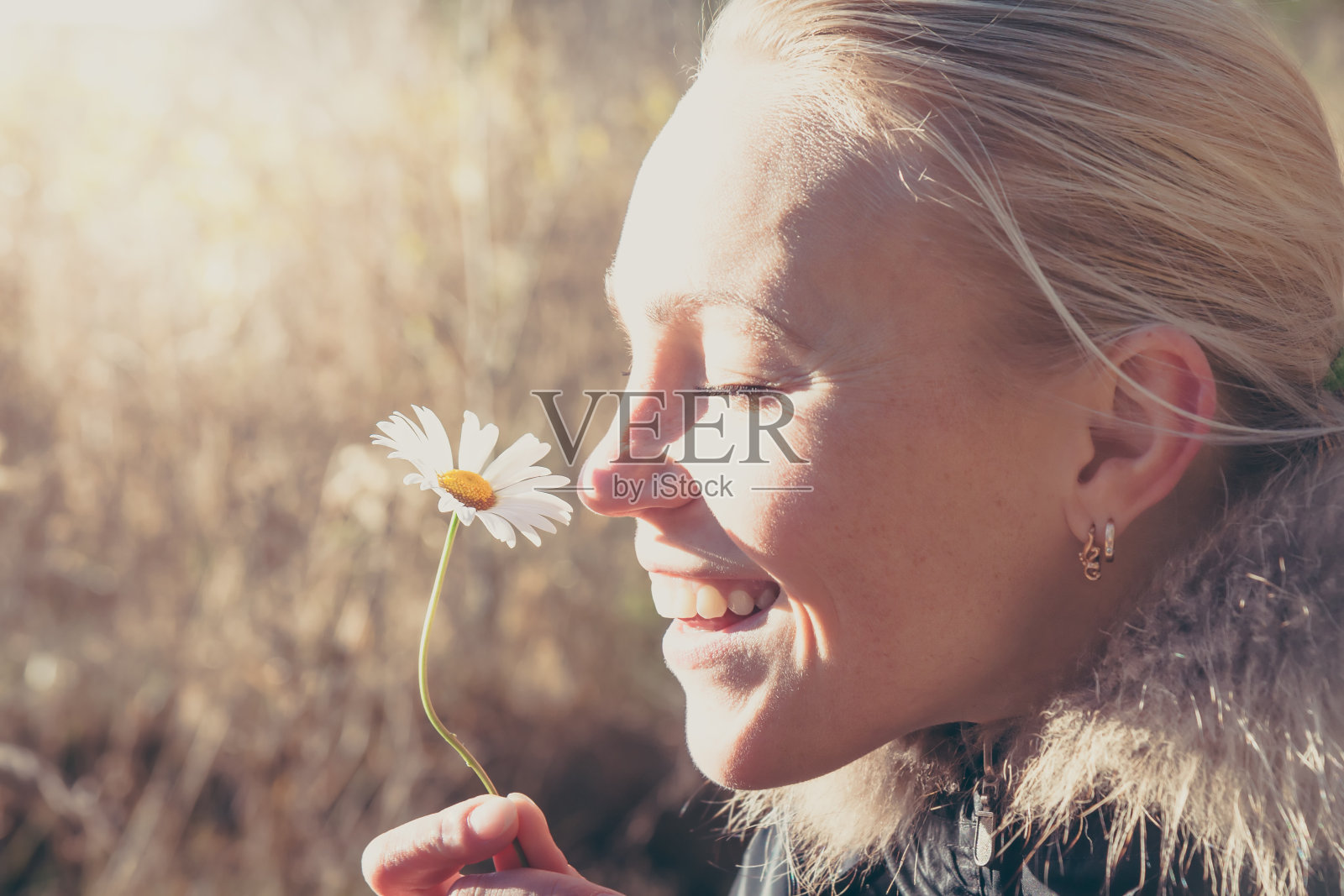 快乐的女人闻着雏菊花挂在手里照片摄影图片