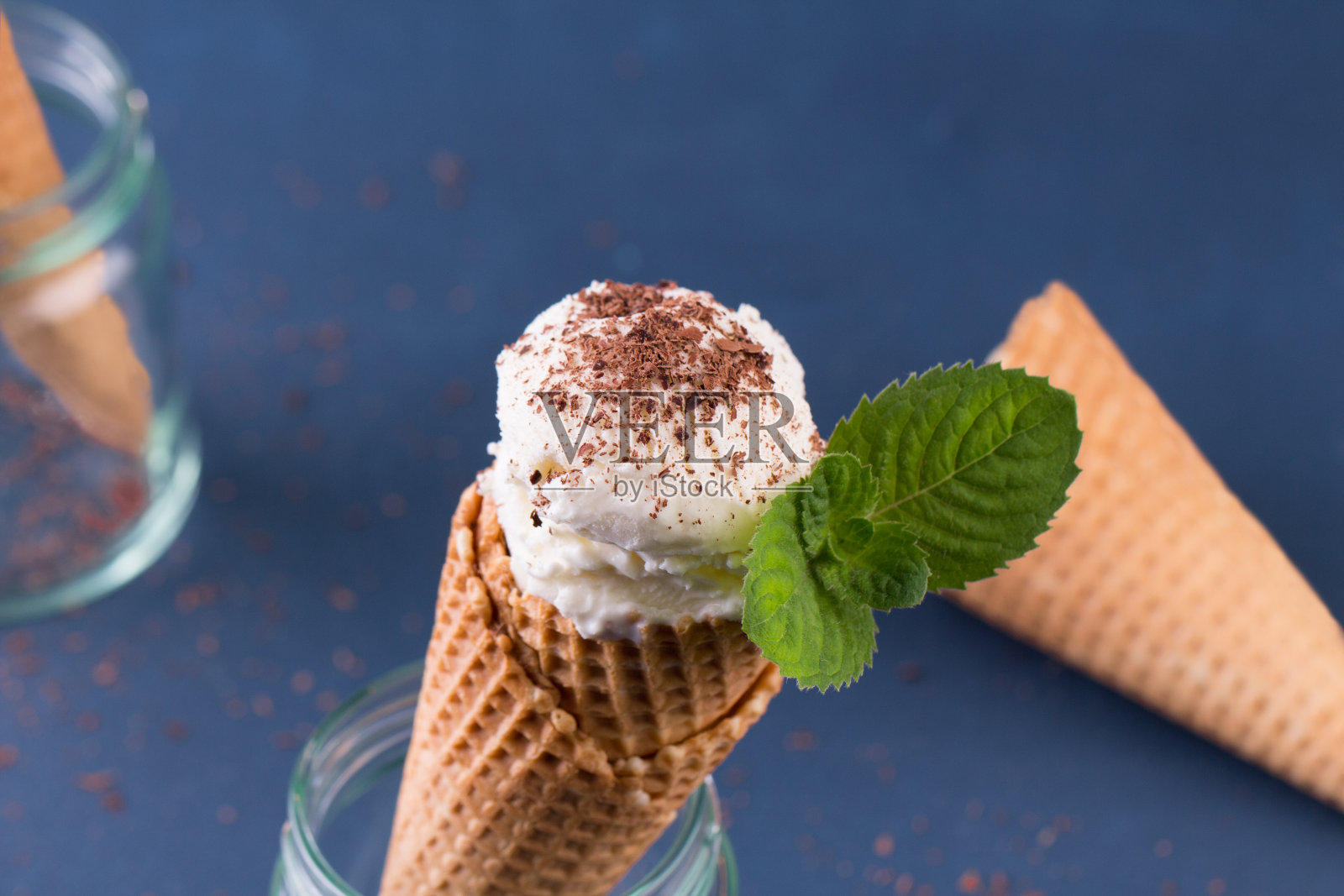 传统的华夫筒冰淇淋和勺子在蓝色的石头桌上。一种装满冰淇淋的蛋卷照片摄影图片