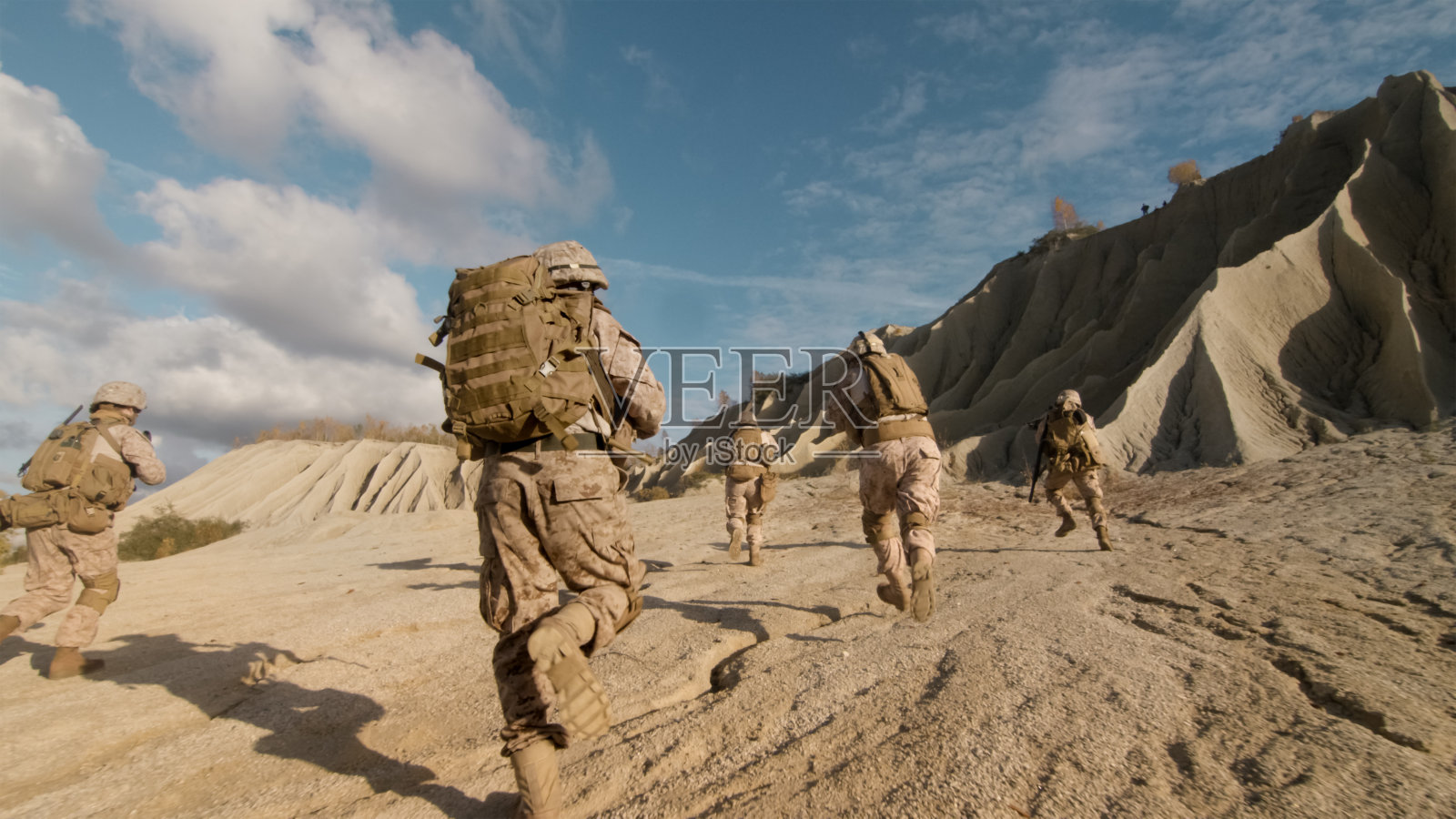 沙漠军事行动中，小分队向前奔跑攻击敌人的镜头。照片摄影图片