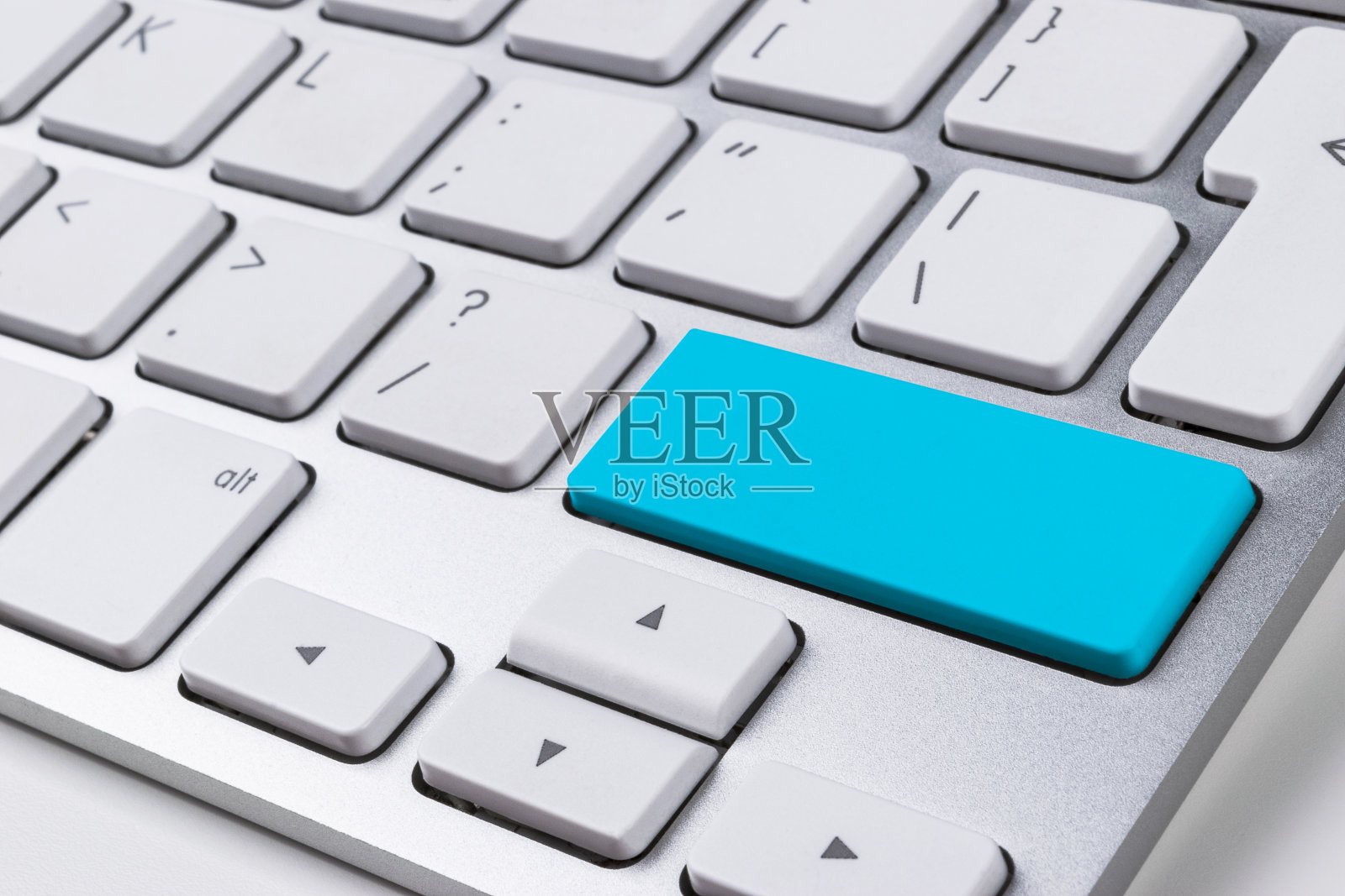 近视图的电脑笔记本键盘与一个蓝色按钮的办公室白色桌子，技术背景，空白的文字照片摄影图片