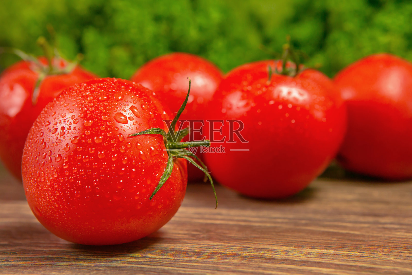 木桌上放着新鲜成熟的西红柿，背景是绿色沙拉。新鲜蔬菜。照片摄影图片