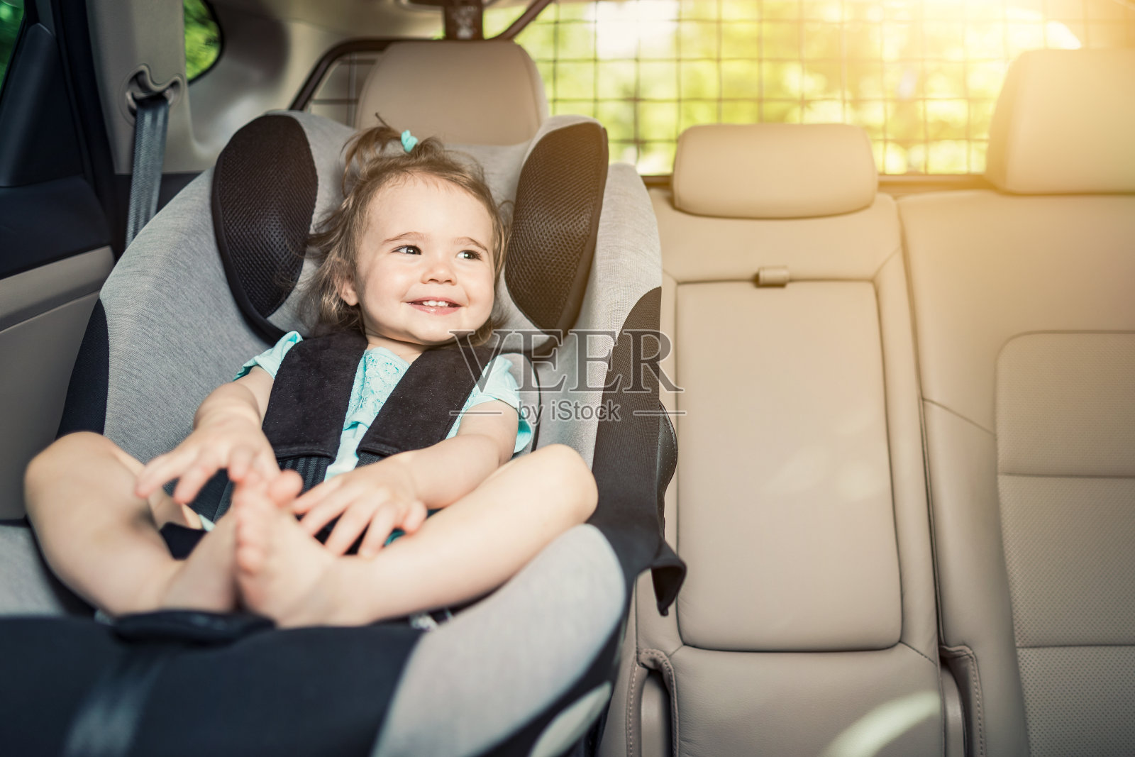 女婴扣在她的汽车座椅上。照片摄影图片