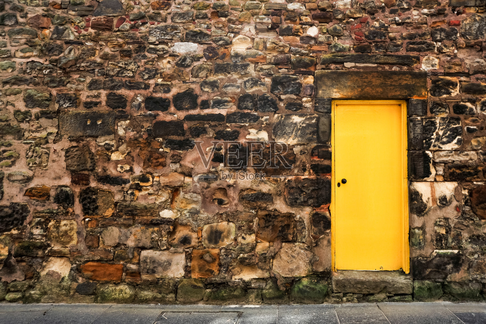 黄色的门靠在一堵石墙上照片摄影图片