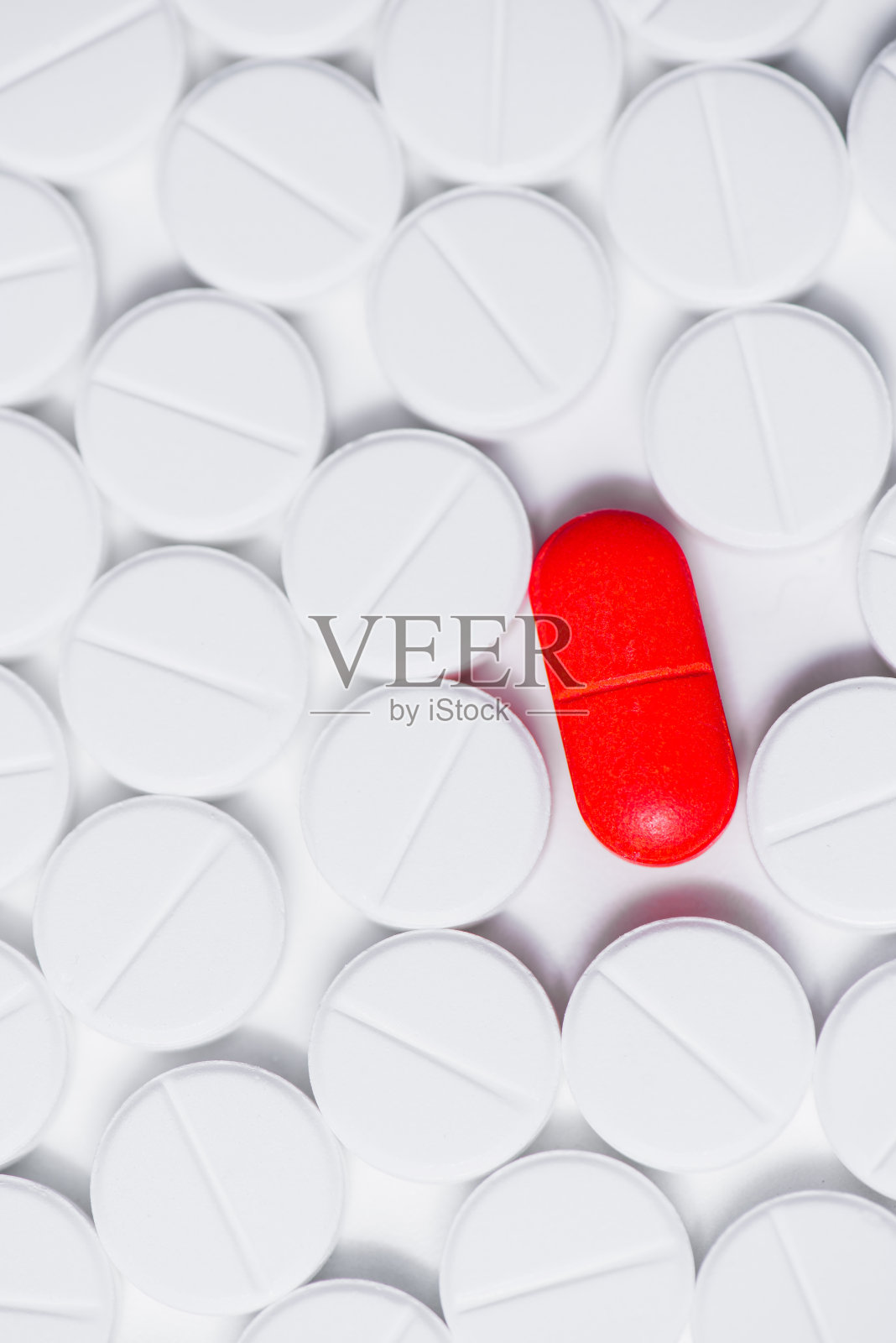 一颗红色的药丸，周围是白色的处方药丸，背景是白色照片摄影图片