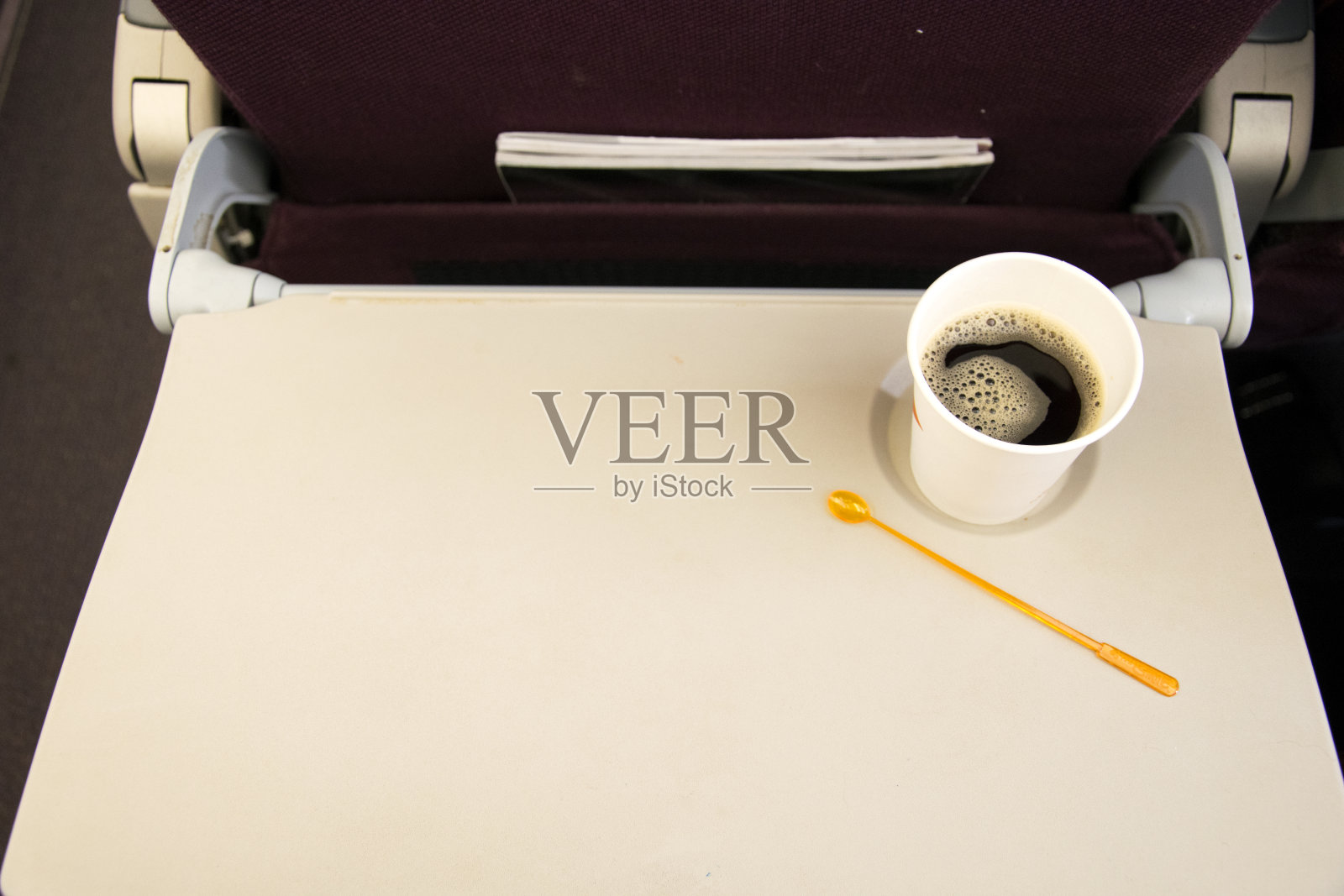 飞机椅背上的小桌板，纸杯咖啡。照片摄影图片
