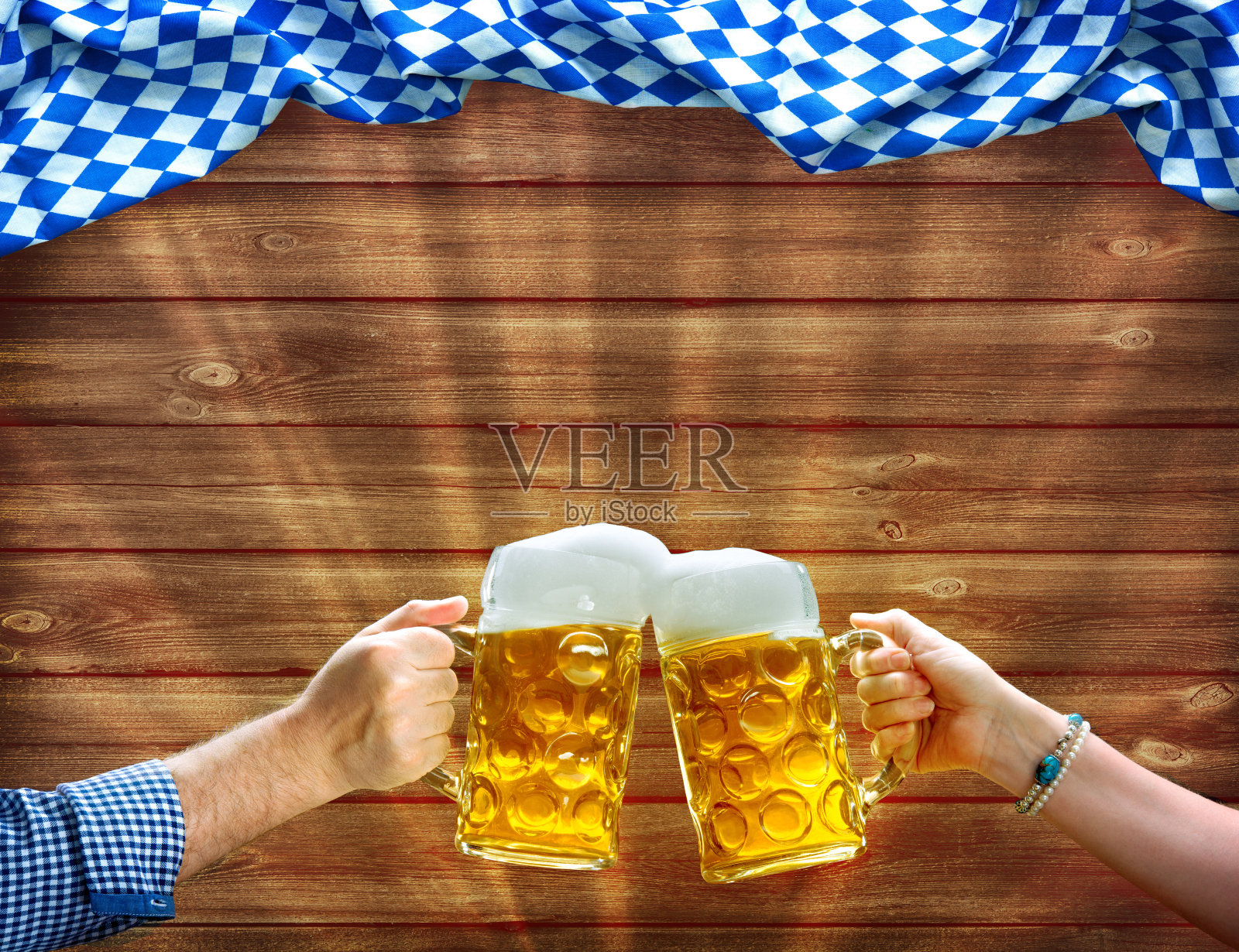 双手在巴伐利亚旗帜下举着啤酒杯照片摄影图片