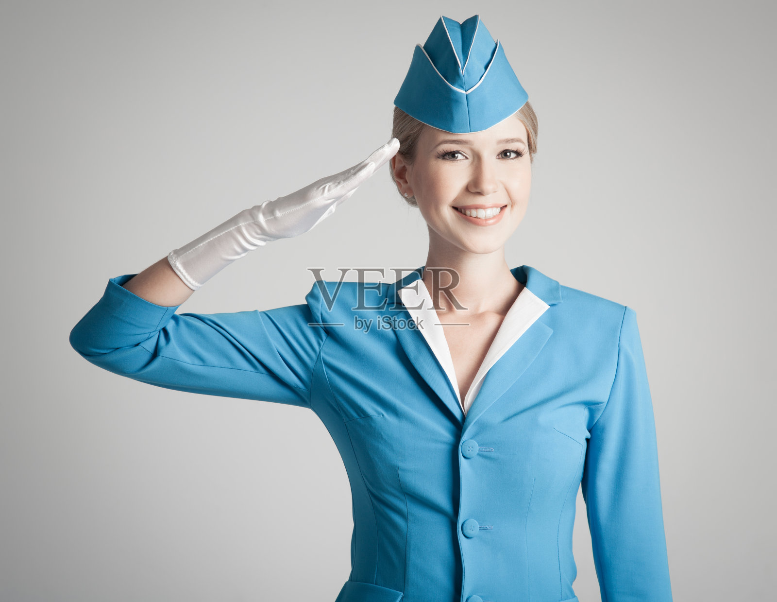 在灰色背景下穿着蓝色制服的迷人空姐照片摄影图片