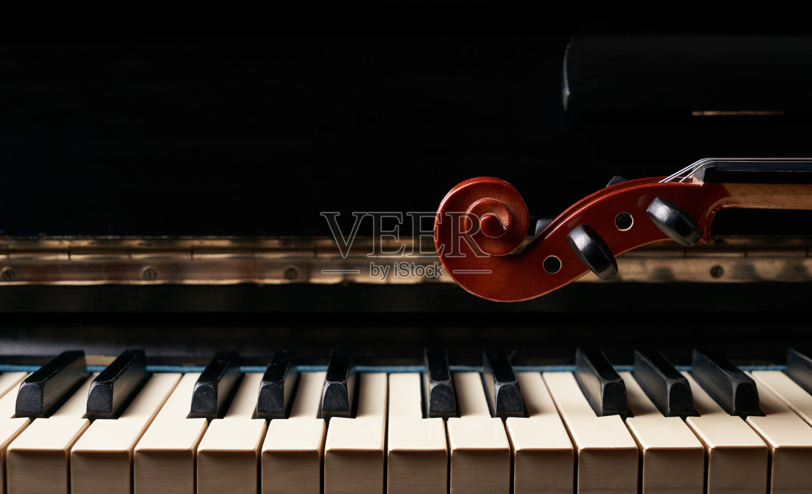 古典音乐中的弦乐器小提琴在钢琴琴键上。照片摄影图片
