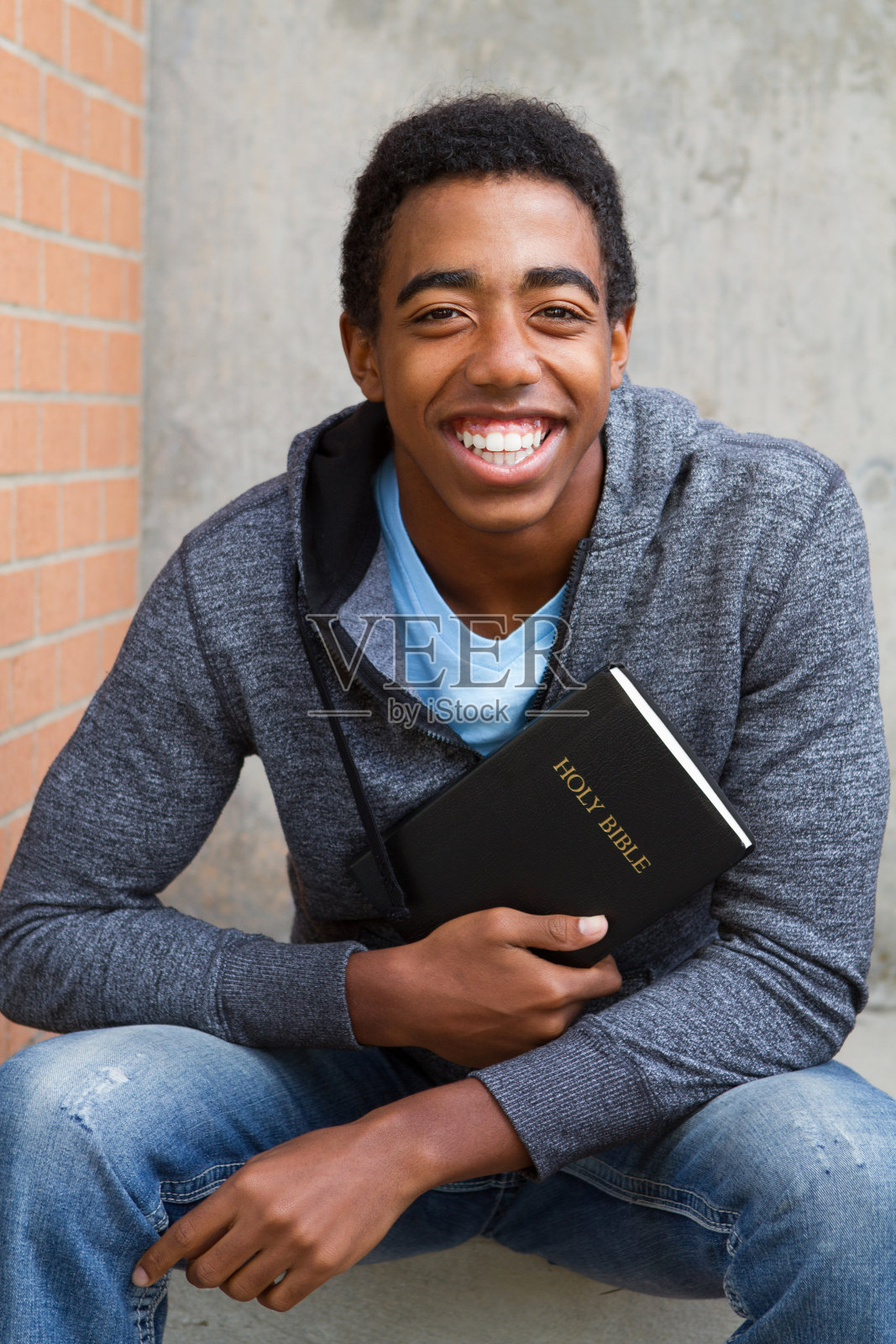 一个少年拿着一本圣经。照片摄影图片