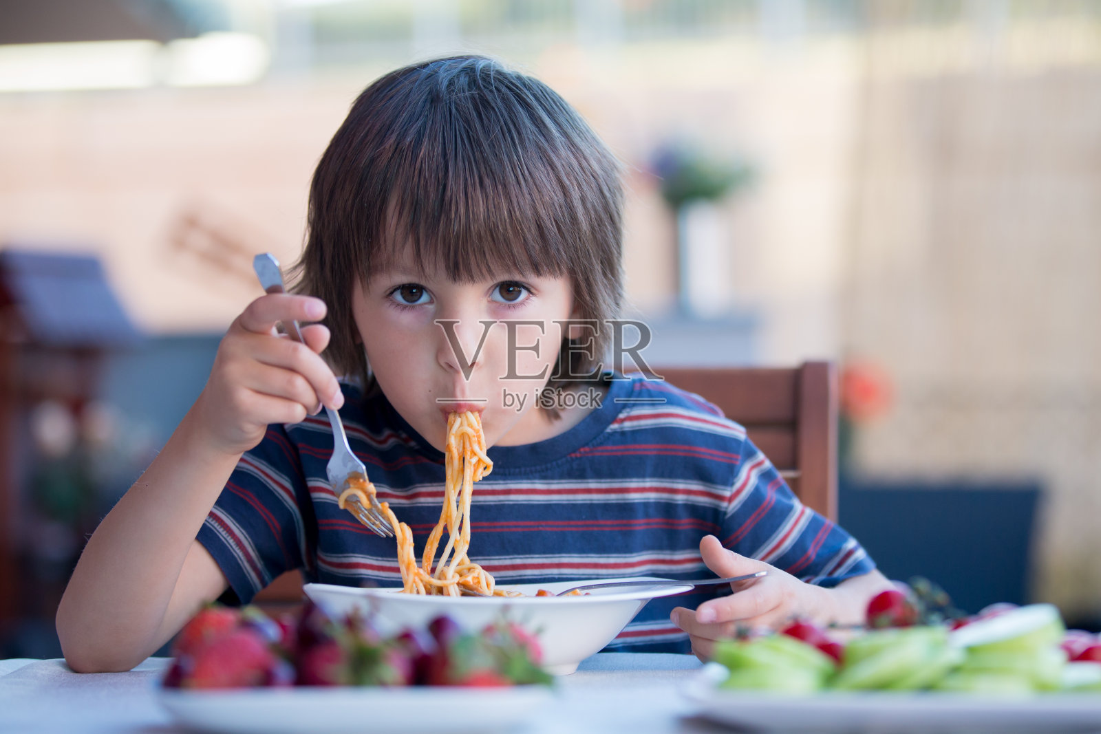 可爱的孩子，学前班的小男孩，午餐在户外吃意大利面照片摄影图片