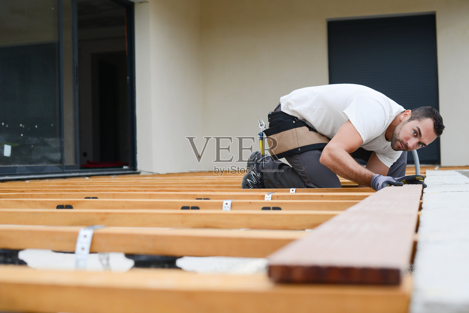 英俊的年轻木匠正在新房子的工地上安装一个木地板室外露台照片摄影图片