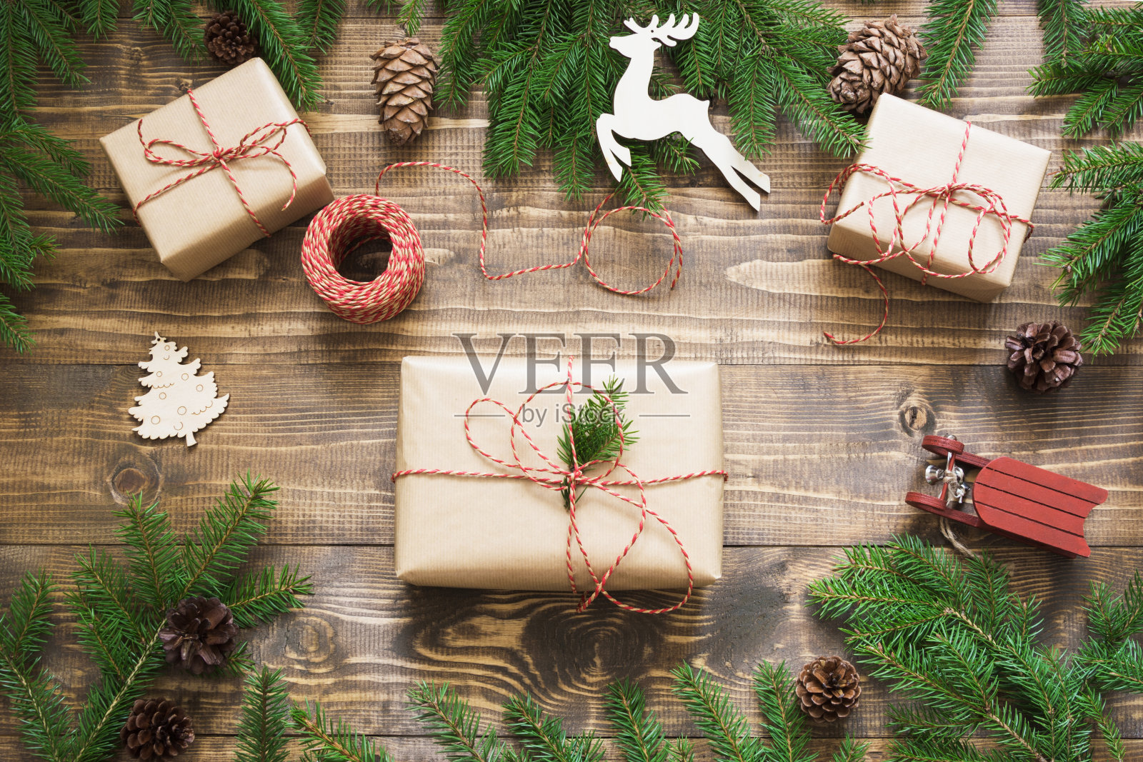 圣诞礼盒和礼物包装在牛皮纸和装饰在木板上。平的。前视图。照片摄影图片