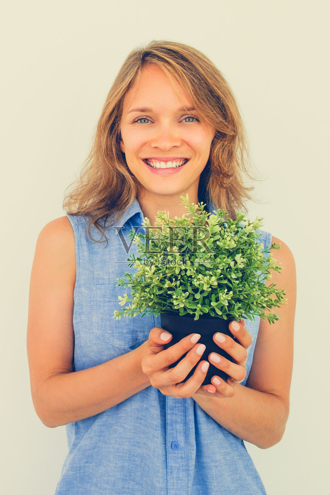 快乐年轻美丽的女人抱着盆栽植物照片摄影图片