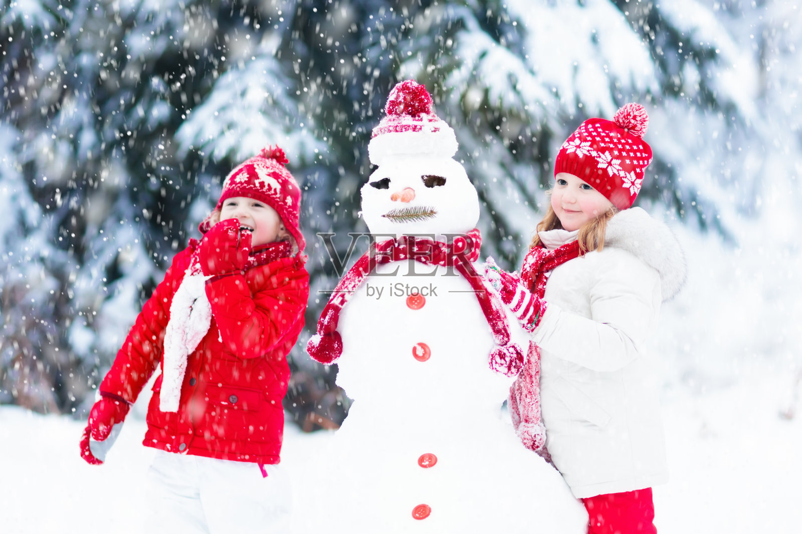 孩子们建造雪人。孩子们在雪。冬天的乐趣。照片摄影图片