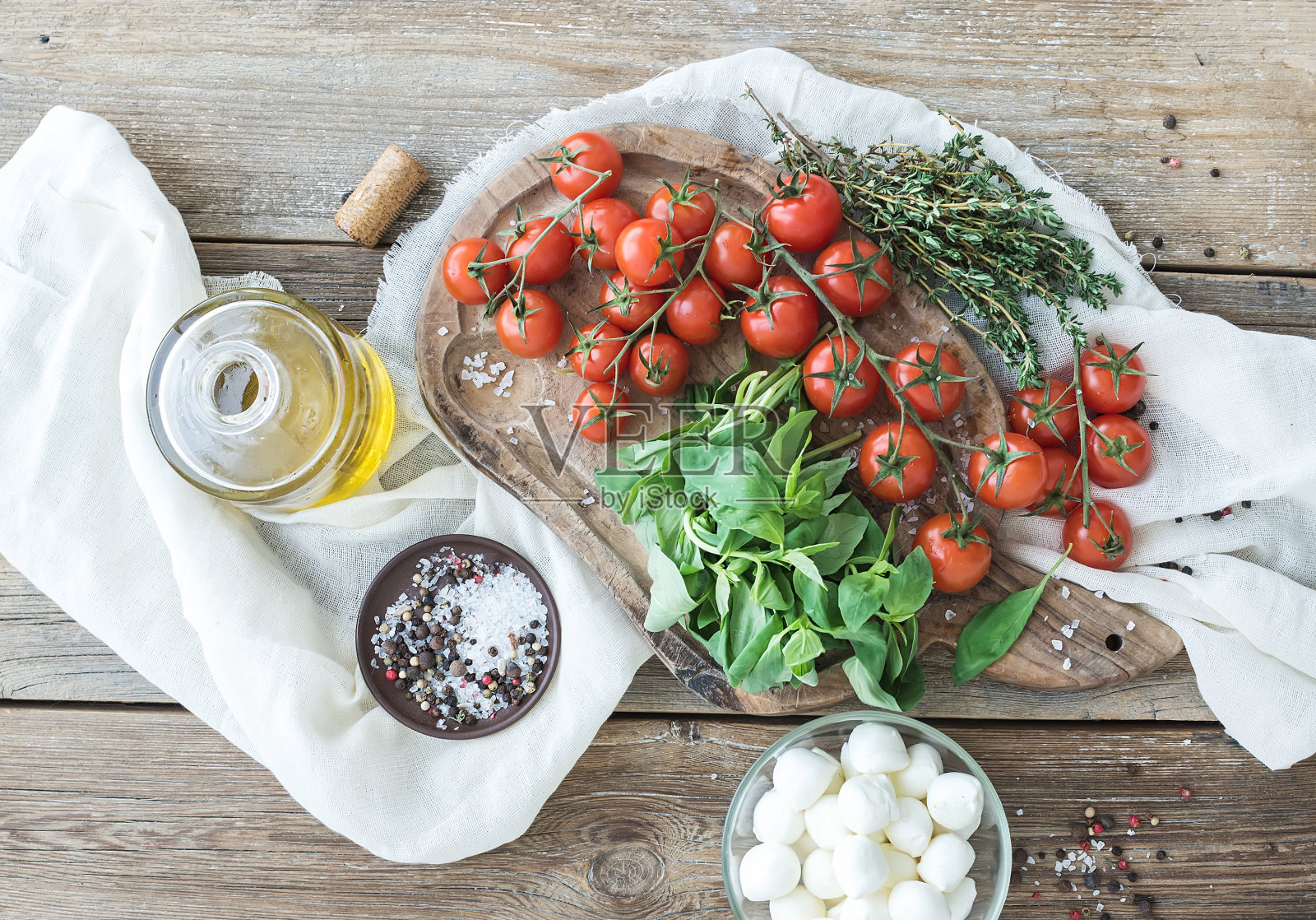 罗勒，樱桃番茄，莫扎雷勒，橄榄油，盐，香料放在乡村砧板上照片摄影图片