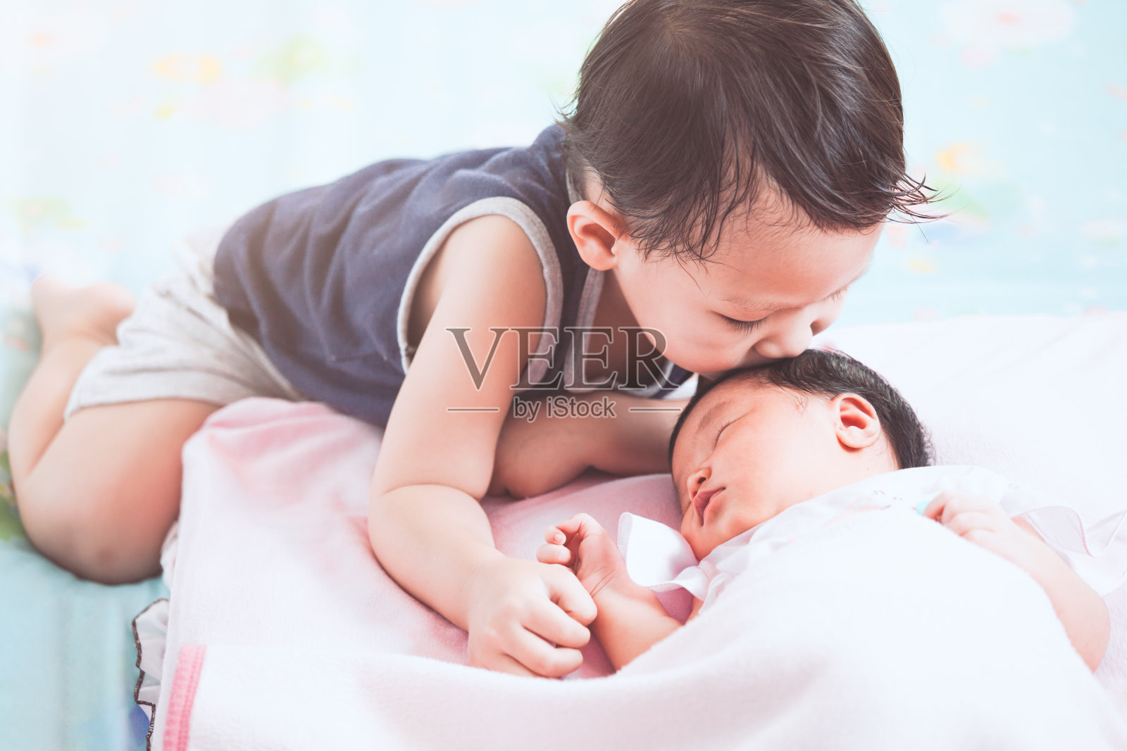可爱的亚洲小男孩亲吻他刚出生的小妹妹照片摄影图片