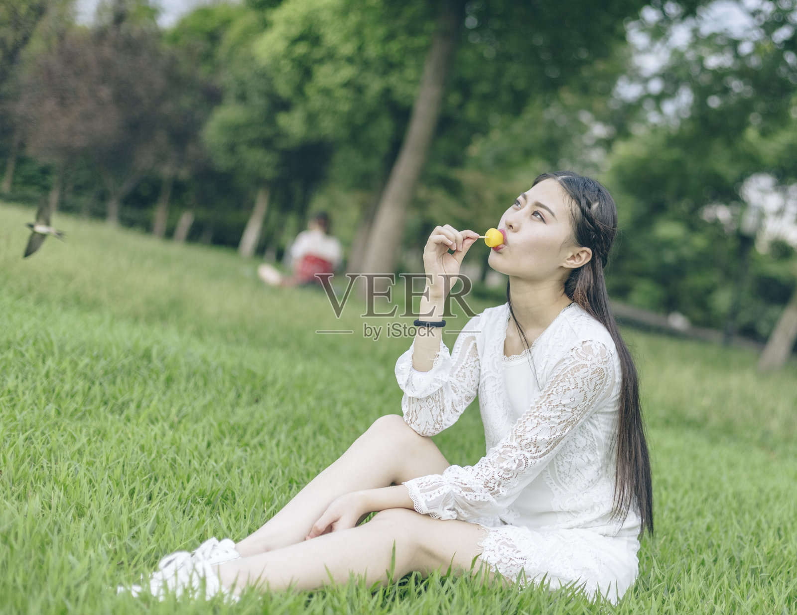 坐在草地上吃冰棒的女人照片摄影图片