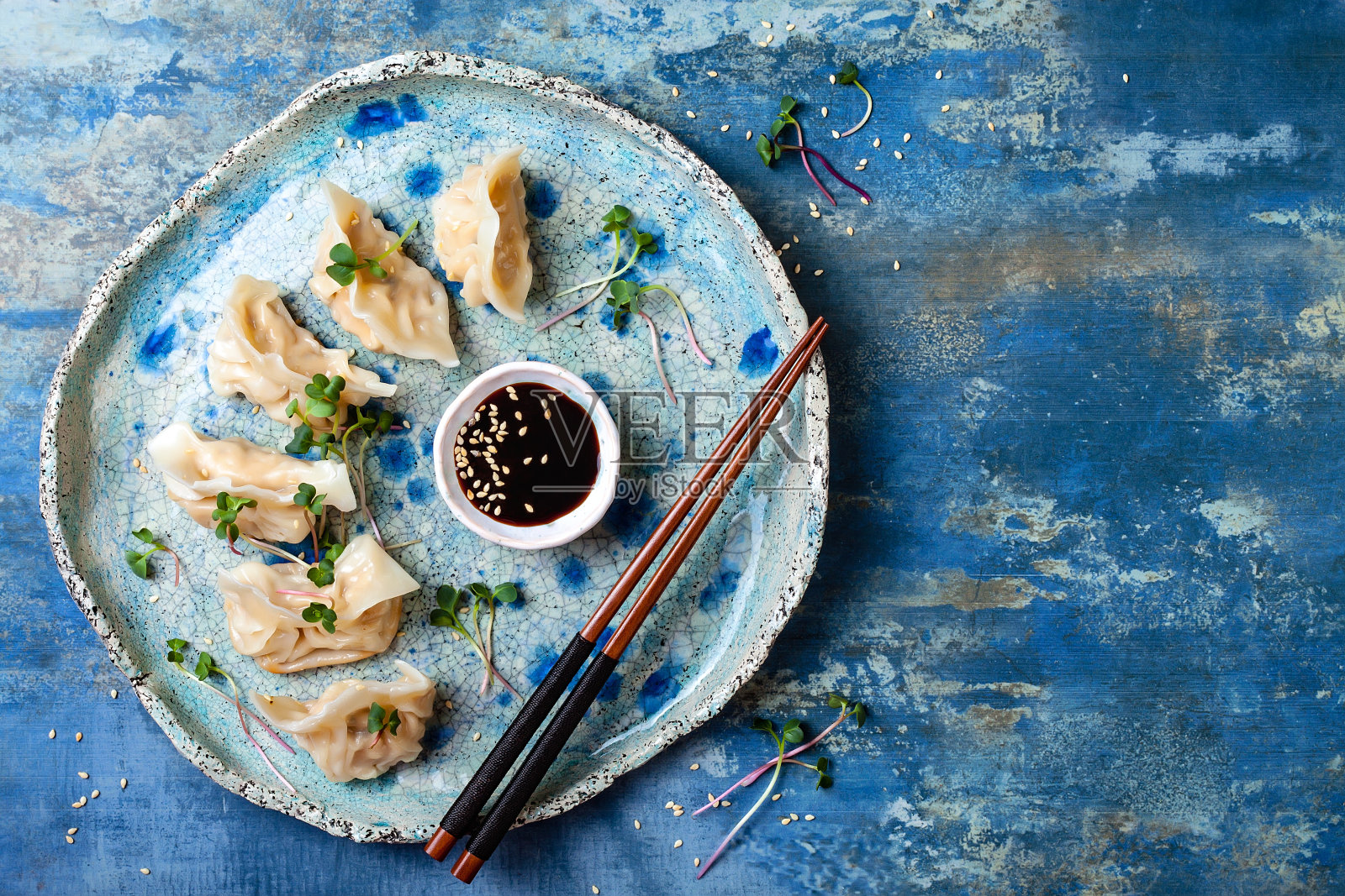 用酱油、芝麻和绿色蔬菜做成的亚洲饺子。传统的中国点心饺子。复制空间，平铺照片摄影图片
