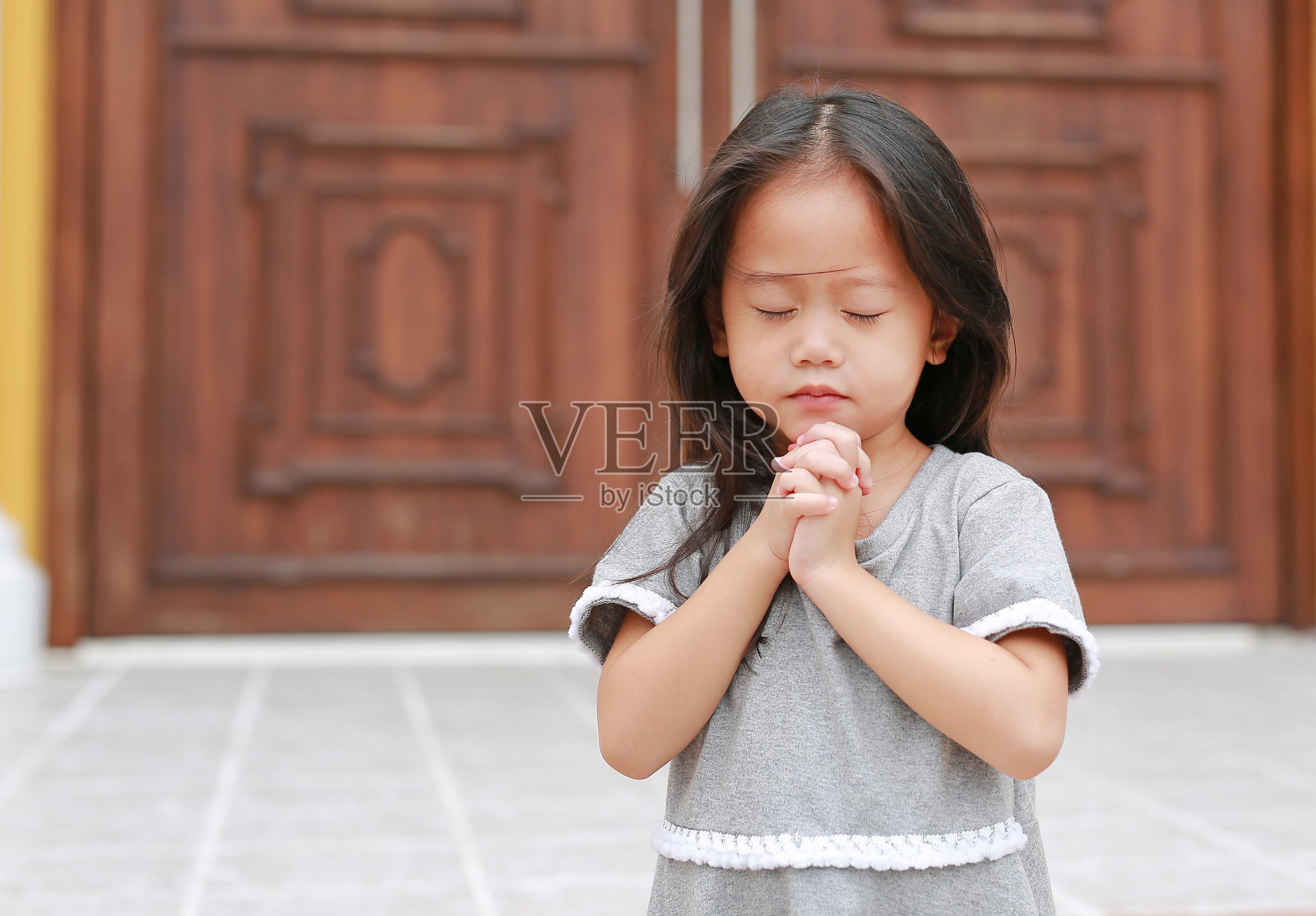 闭上眼睛祈祷的亚洲小女孩。照片摄影图片