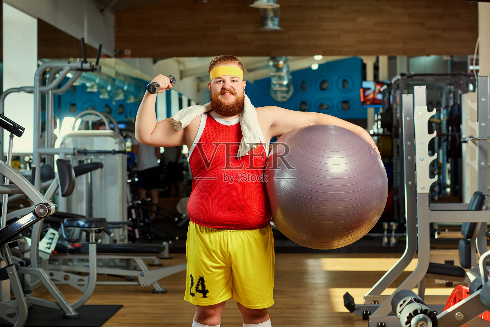 健身房里拿着哑铃的搞笑胖子。照片摄影图片