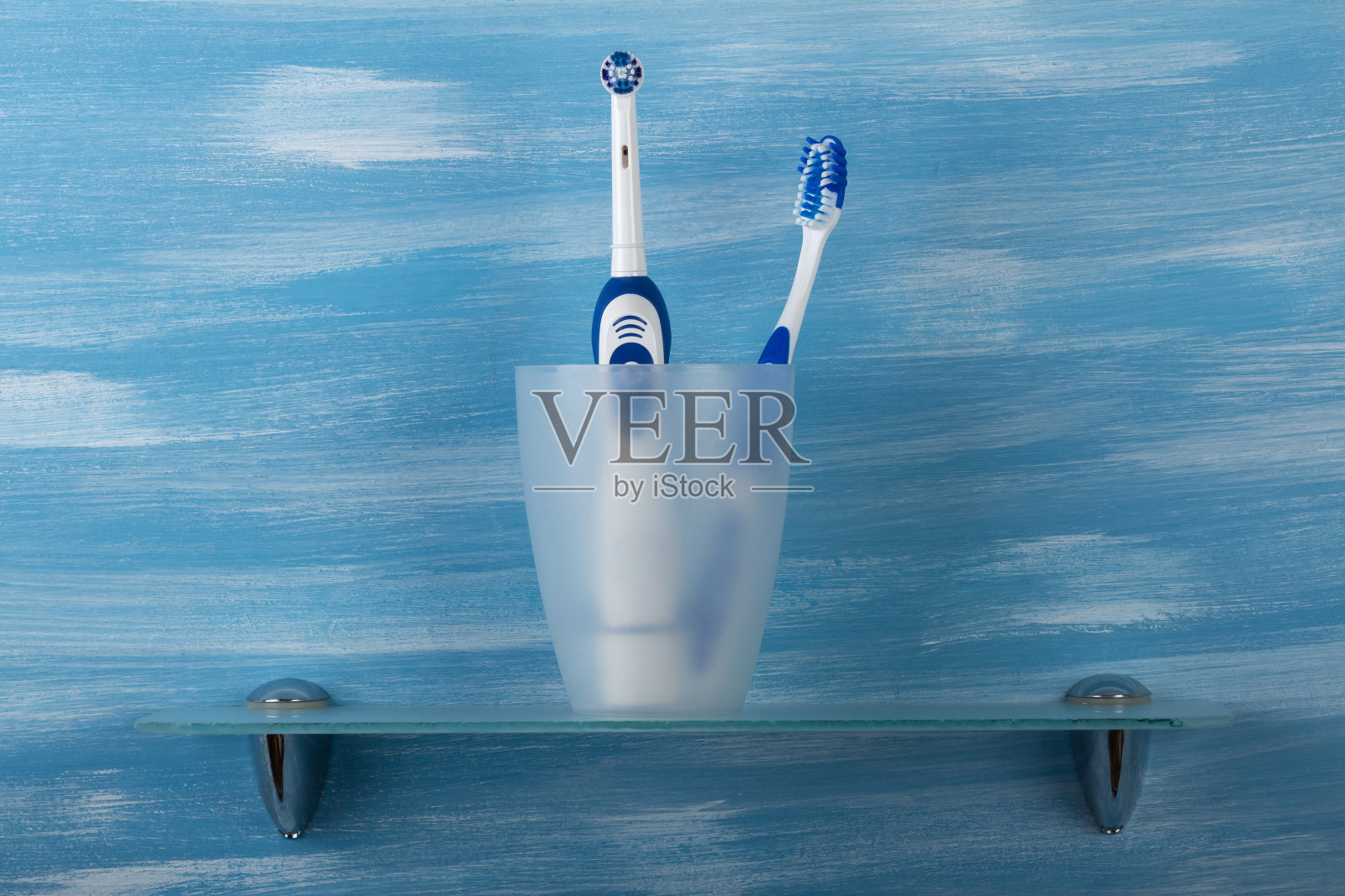 手动牙刷和电动牙刷都是玻璃的，蓝色的照片摄影图片
