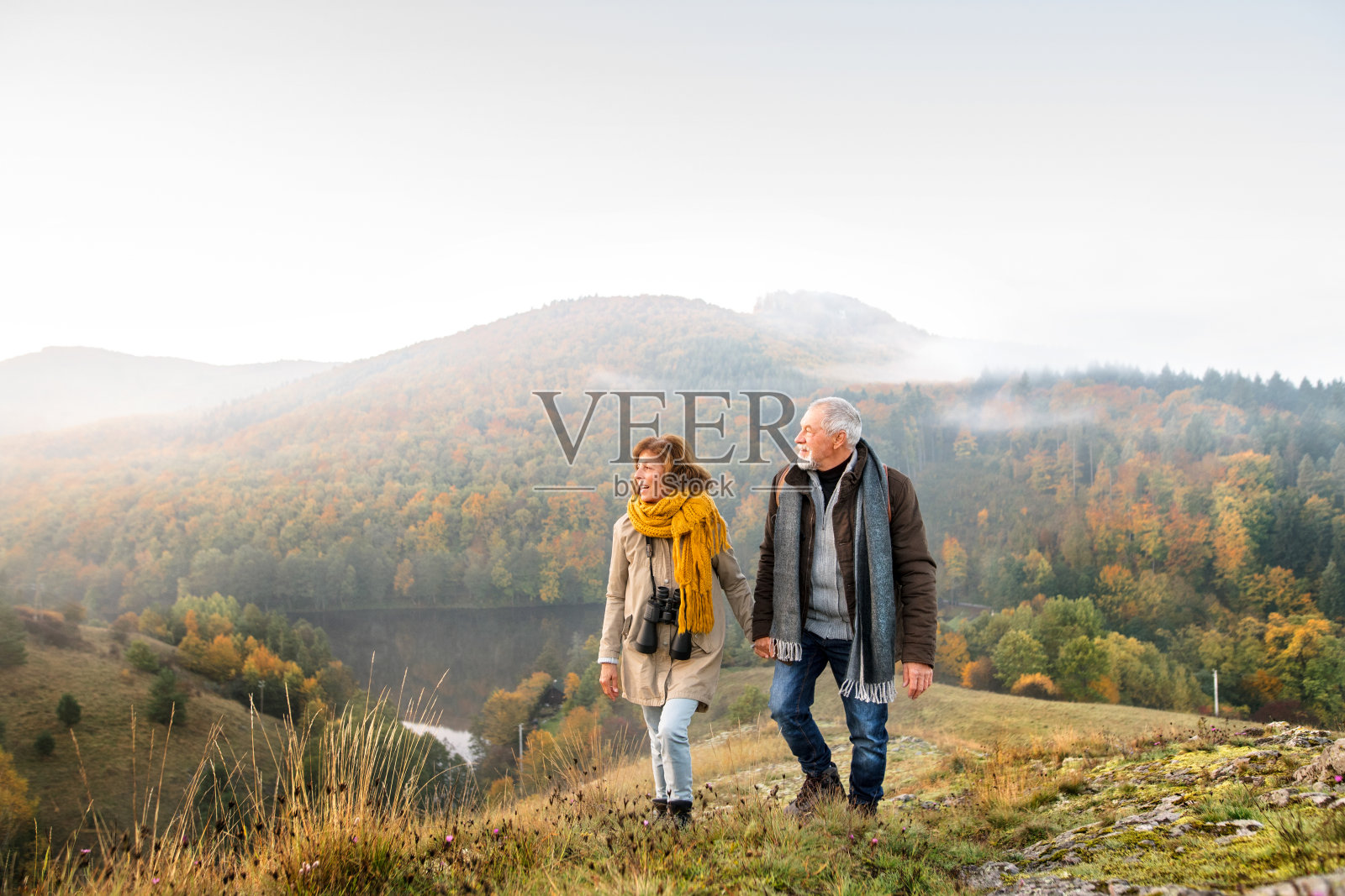 一对老年夫妇在秋天的大自然中散步。照片摄影图片