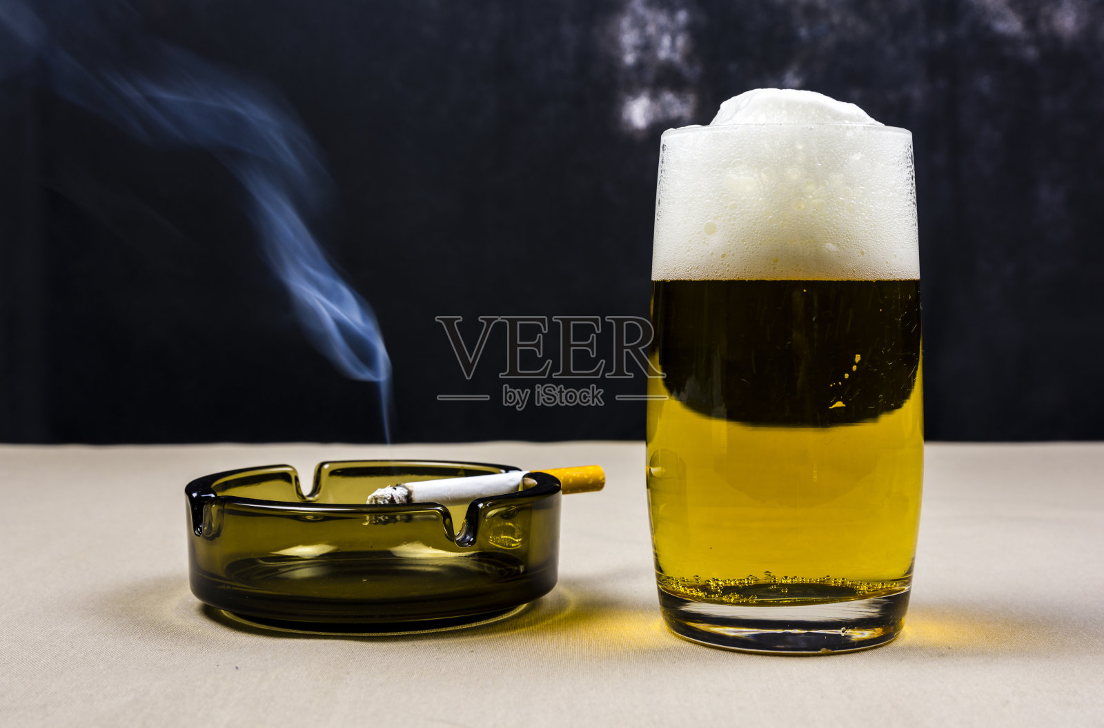 啤酒杯和燃烧的香烟。照片摄影图片