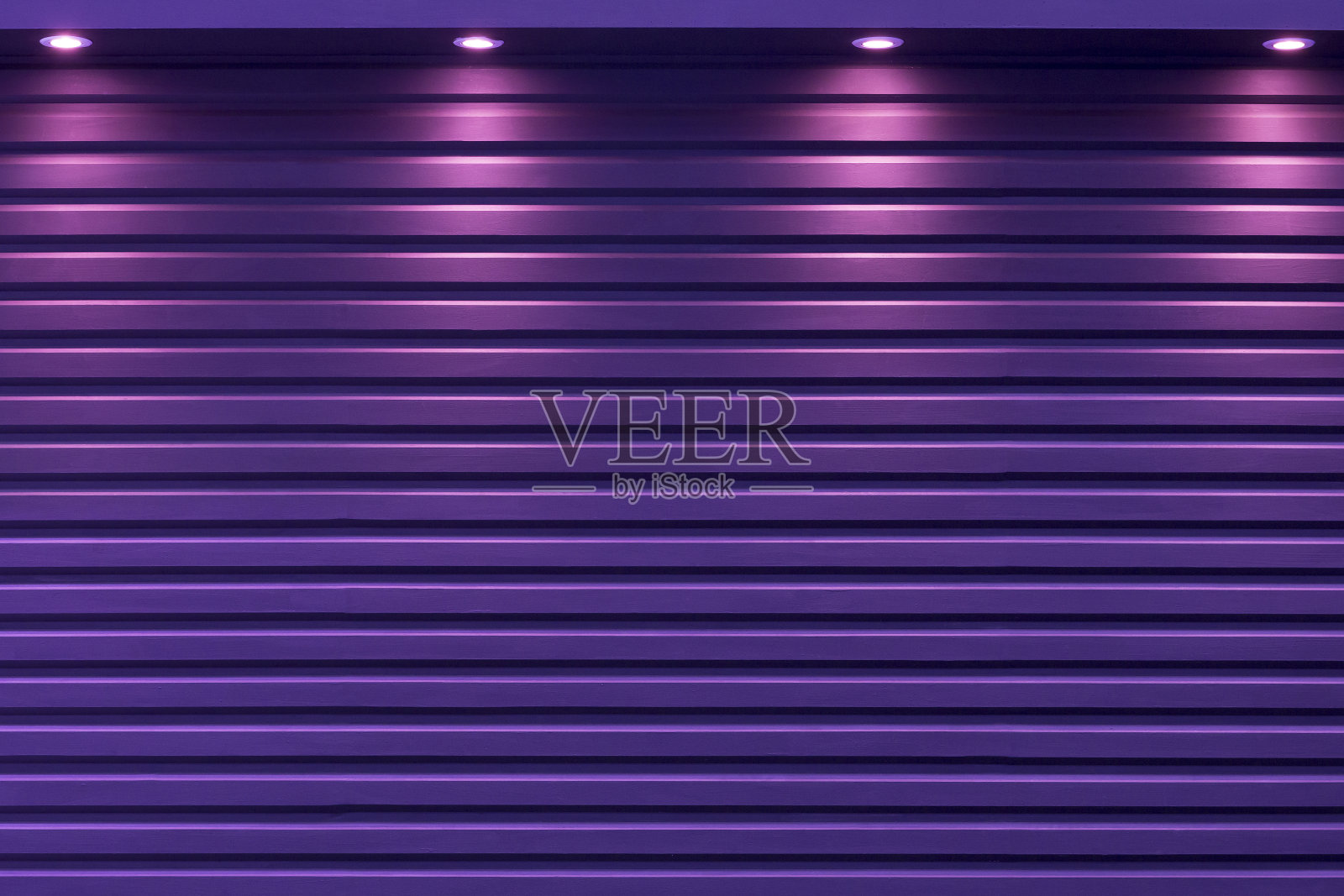 聚光灯背景下的紫色卷帘门。照片摄影图片