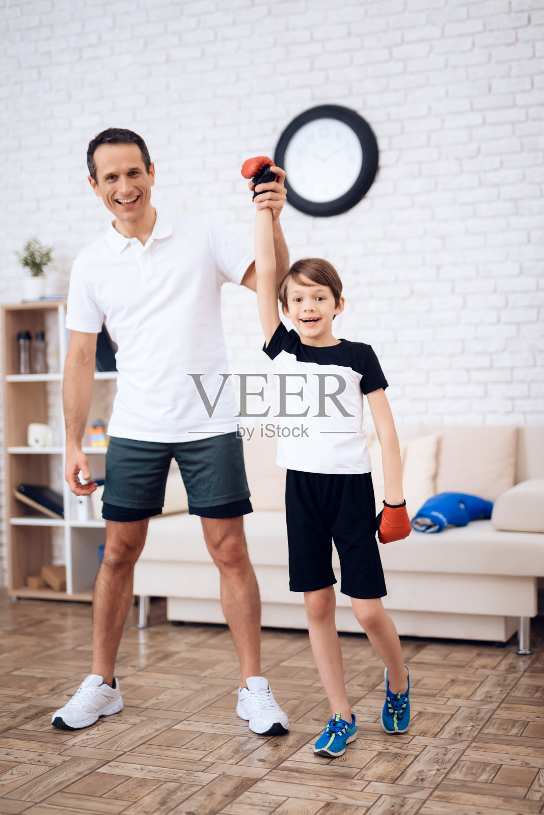 父亲和儿子戴着拳击手套在镜头前摆姿势。照片摄影图片