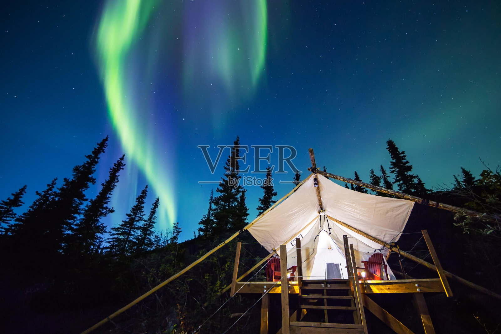 北极光在阿拉斯加的大型帆布豪华露营帐篷上散发着绿色和粉红色的光芒照片摄影图片