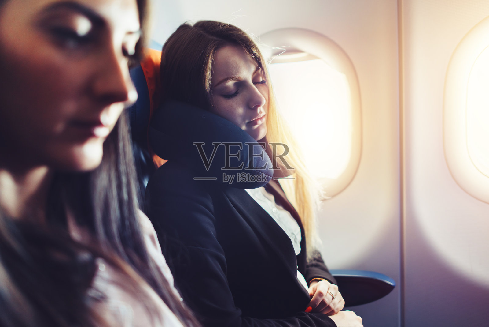两名女商人在出差时使用颈垫睡在飞机上照片摄影图片