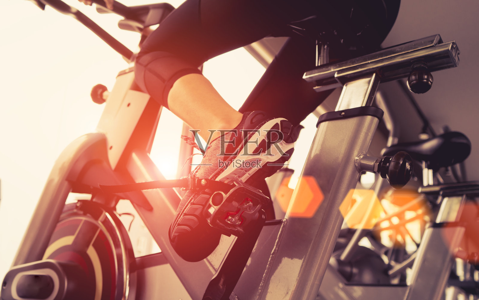 早晨在健身房里用机器有氧运动减肥的女性健身自行车健身，为苗条而结实的健康。照片摄影图片