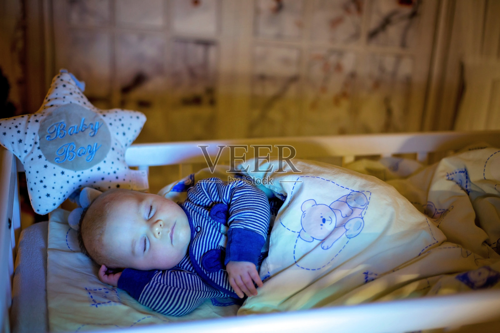 可爱的新生男婴，晚上睡在婴儿床里照片摄影图片